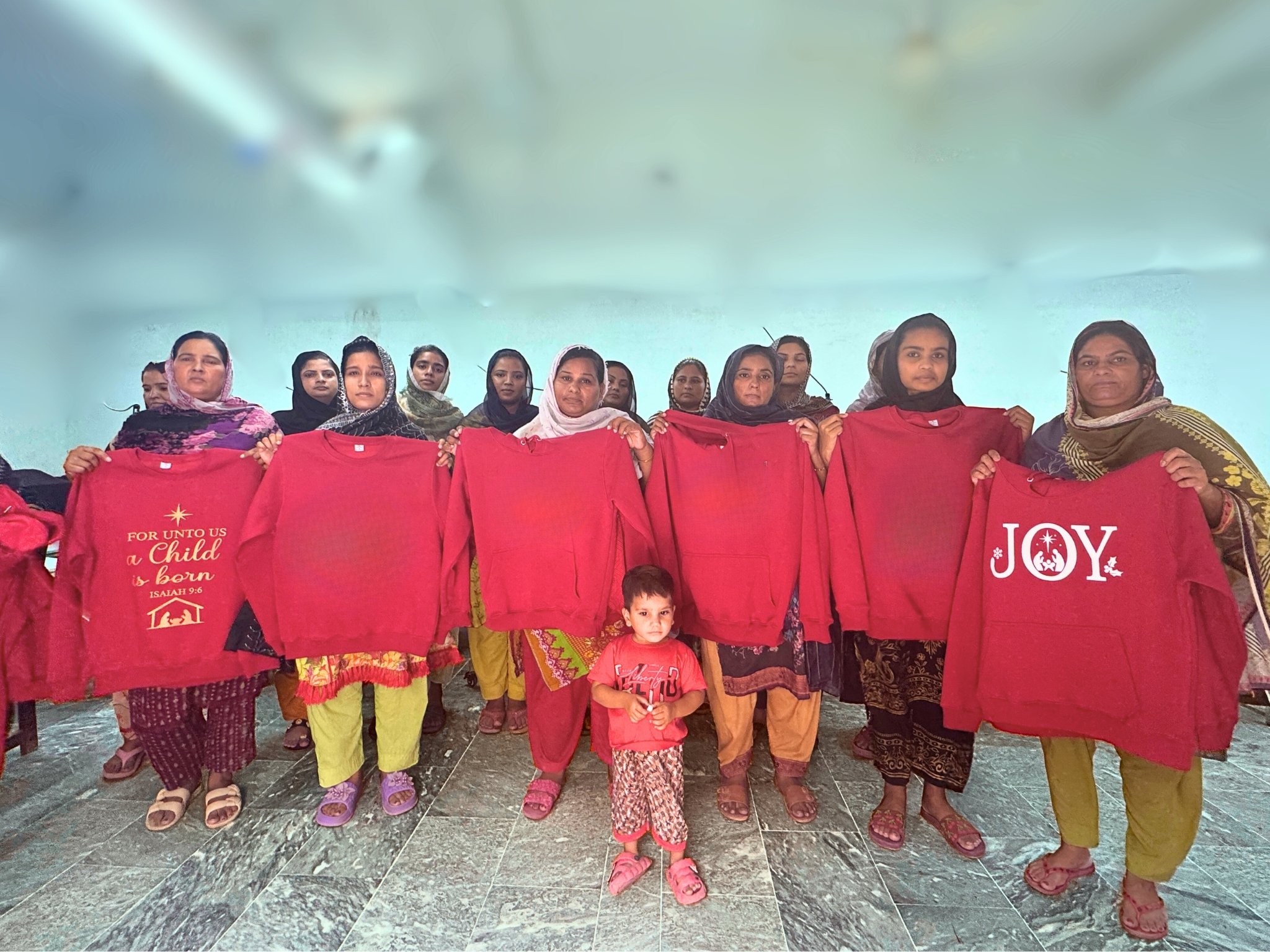 Pakistani women artisans standing together in a garment workshop, empowered through fair employment.