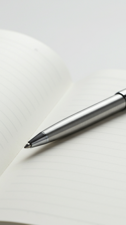 Un stylo argenté posé sur un carnet à pages blanches lignées.