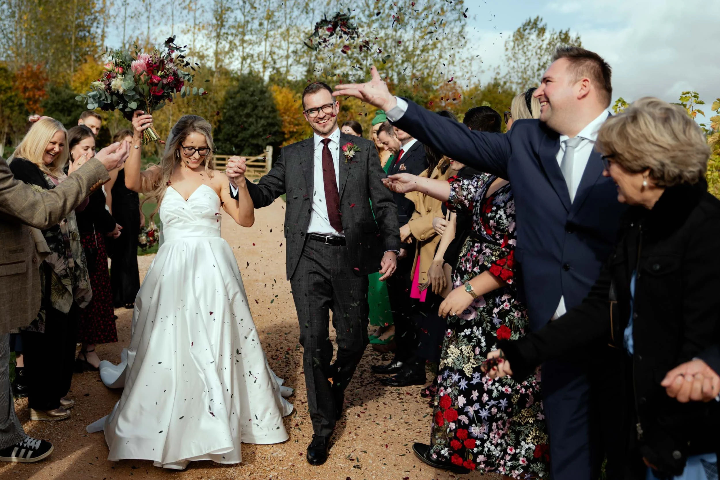 A bride and groom celebrating outside with friends and family after their wedding, throwing confetti in the air.