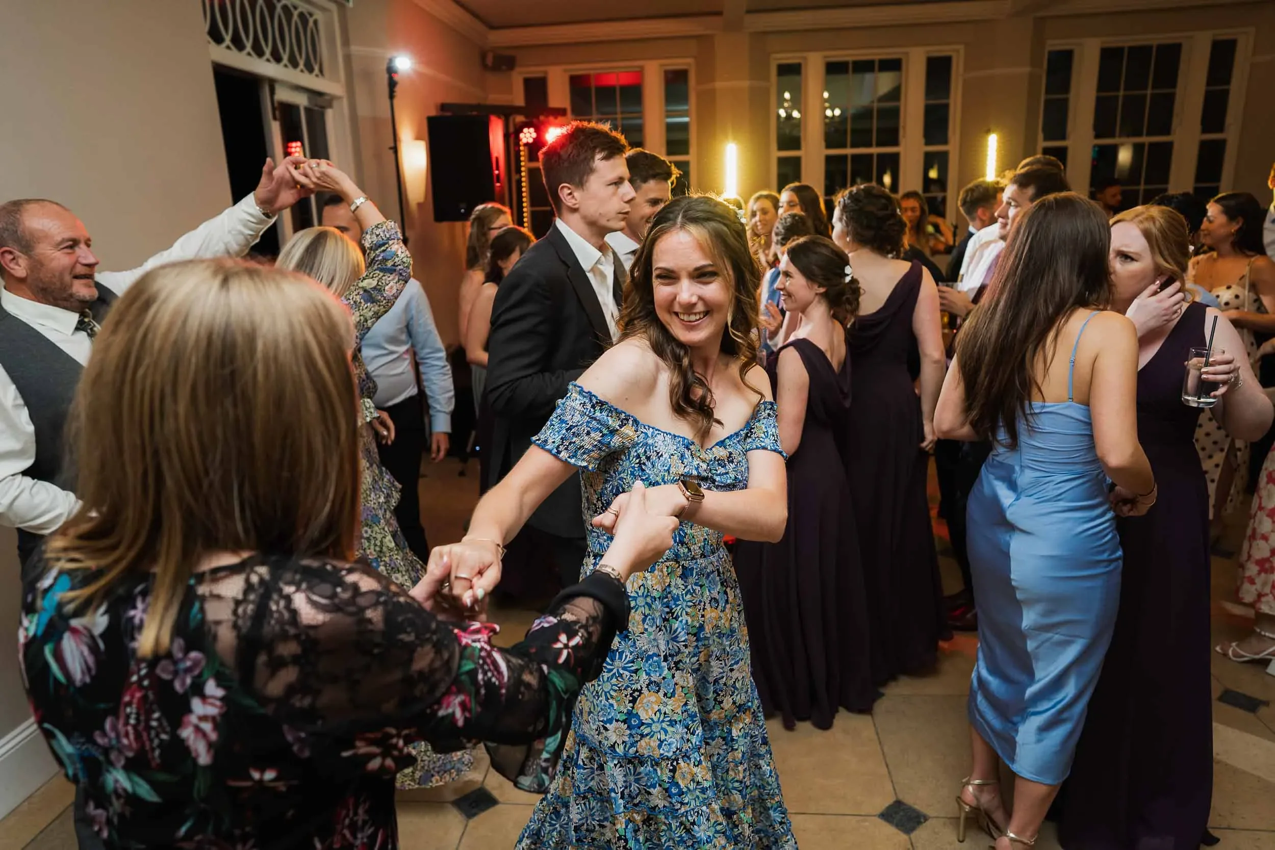 People dancing and having fun at a wedding reception or party in a decorated indoor venue.