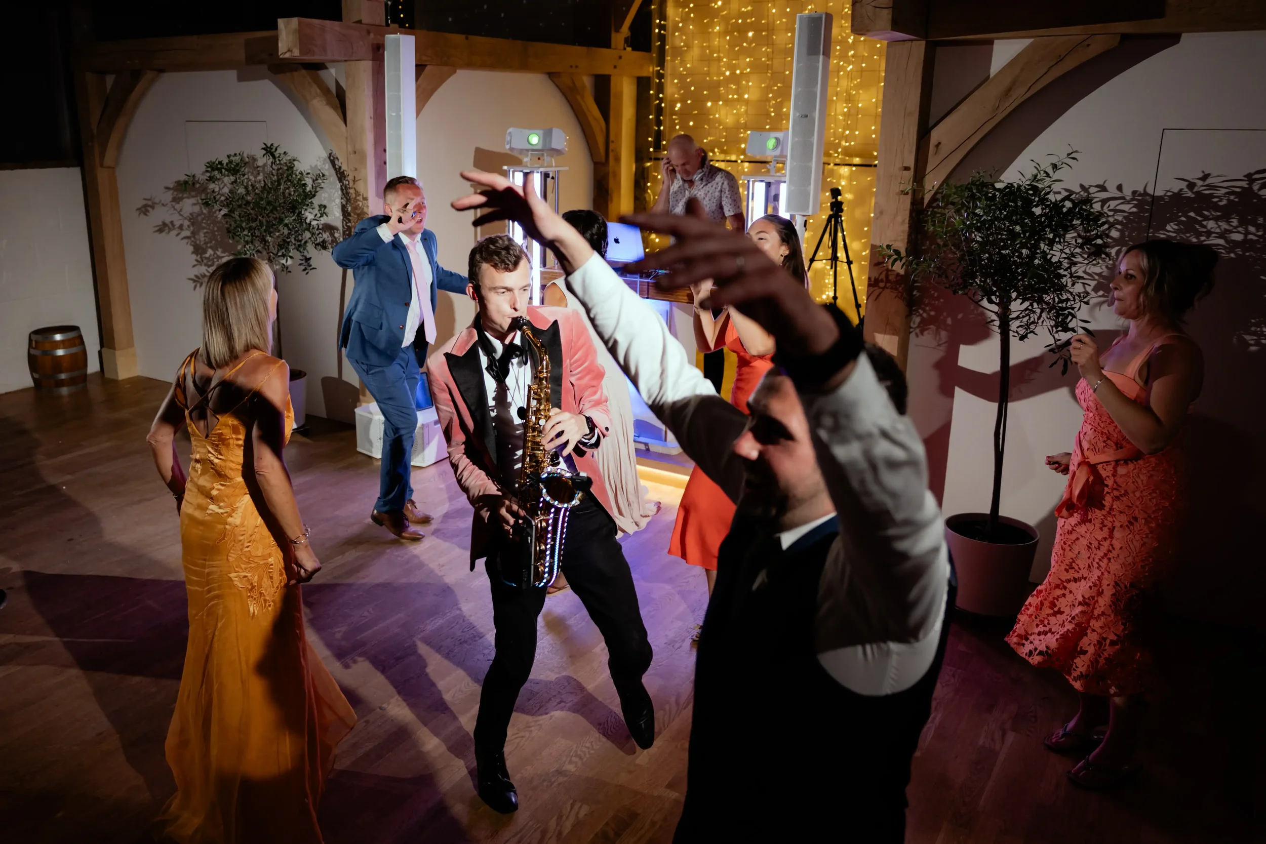 People dancing and enjoying music at a party with a DJ and colorful lights.