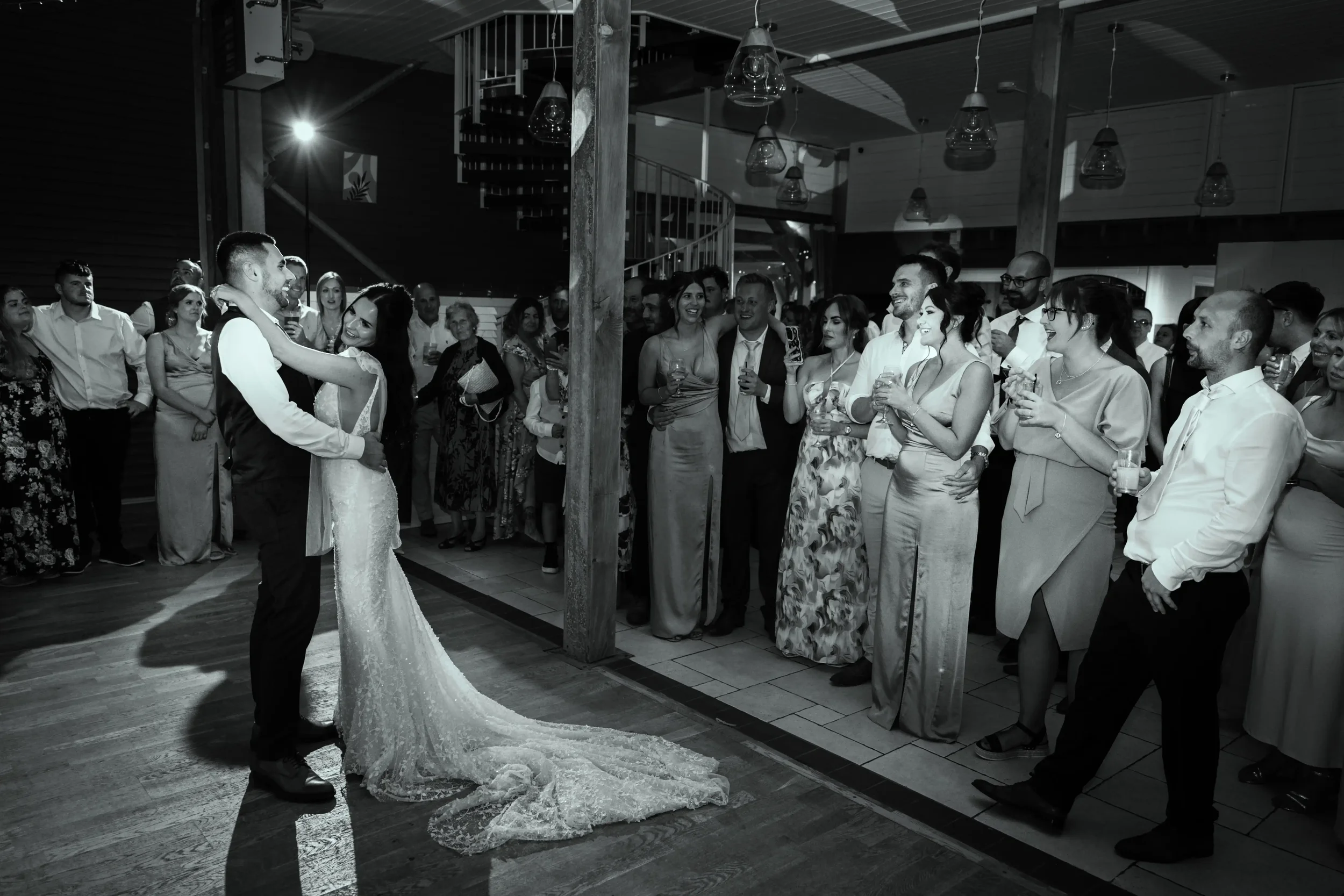 A wedding reception with a bride and groom dancing in front of an audience of guests.