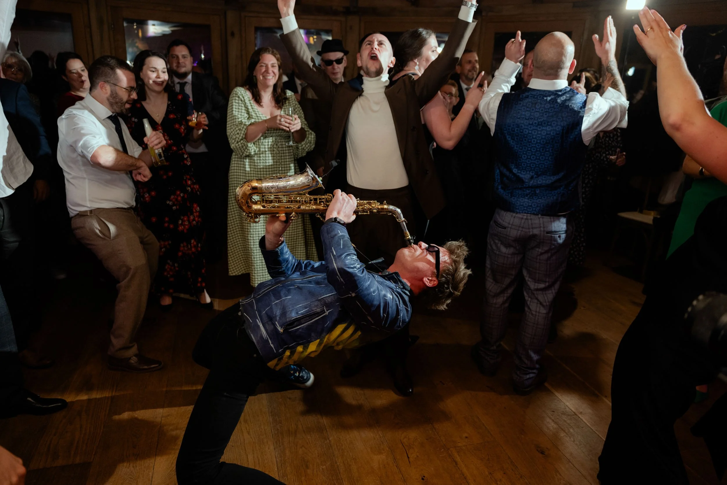 A lively party with a man playing the saxophone passionately while others dance and enjoy.