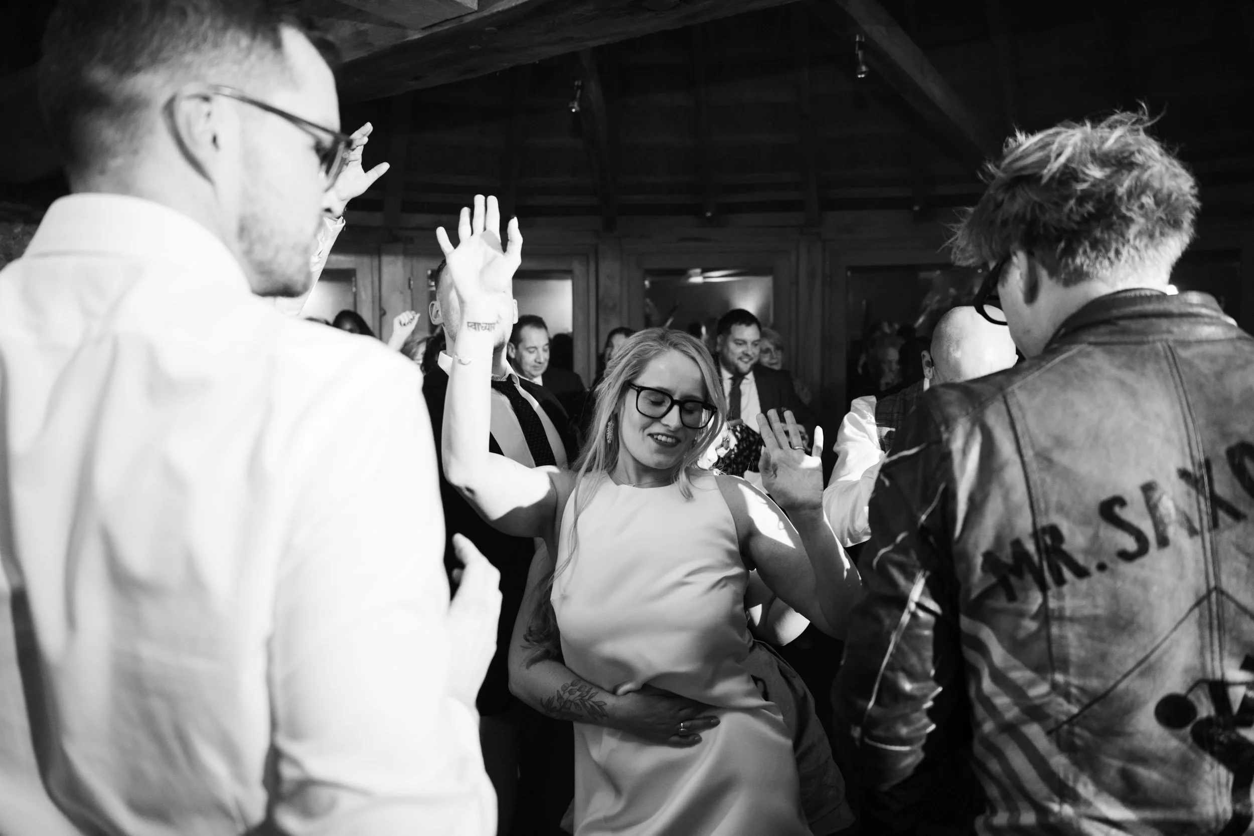 People dancing and enjoying themselves at a lively event or party, with some raising their hands and smiling.