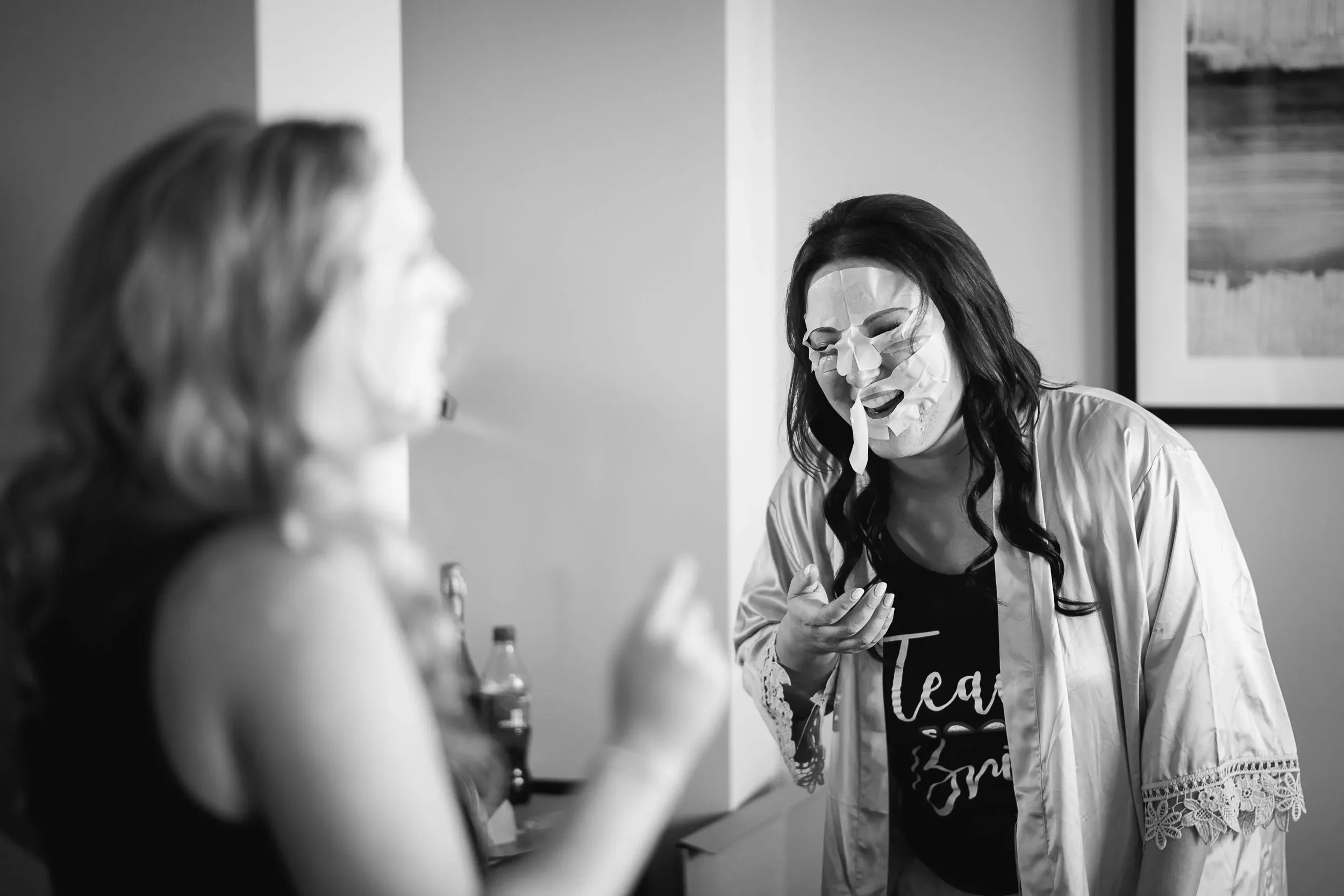 A woman wearing a face mask or mask, engaging in a conversation with another woman in an indoor setting.