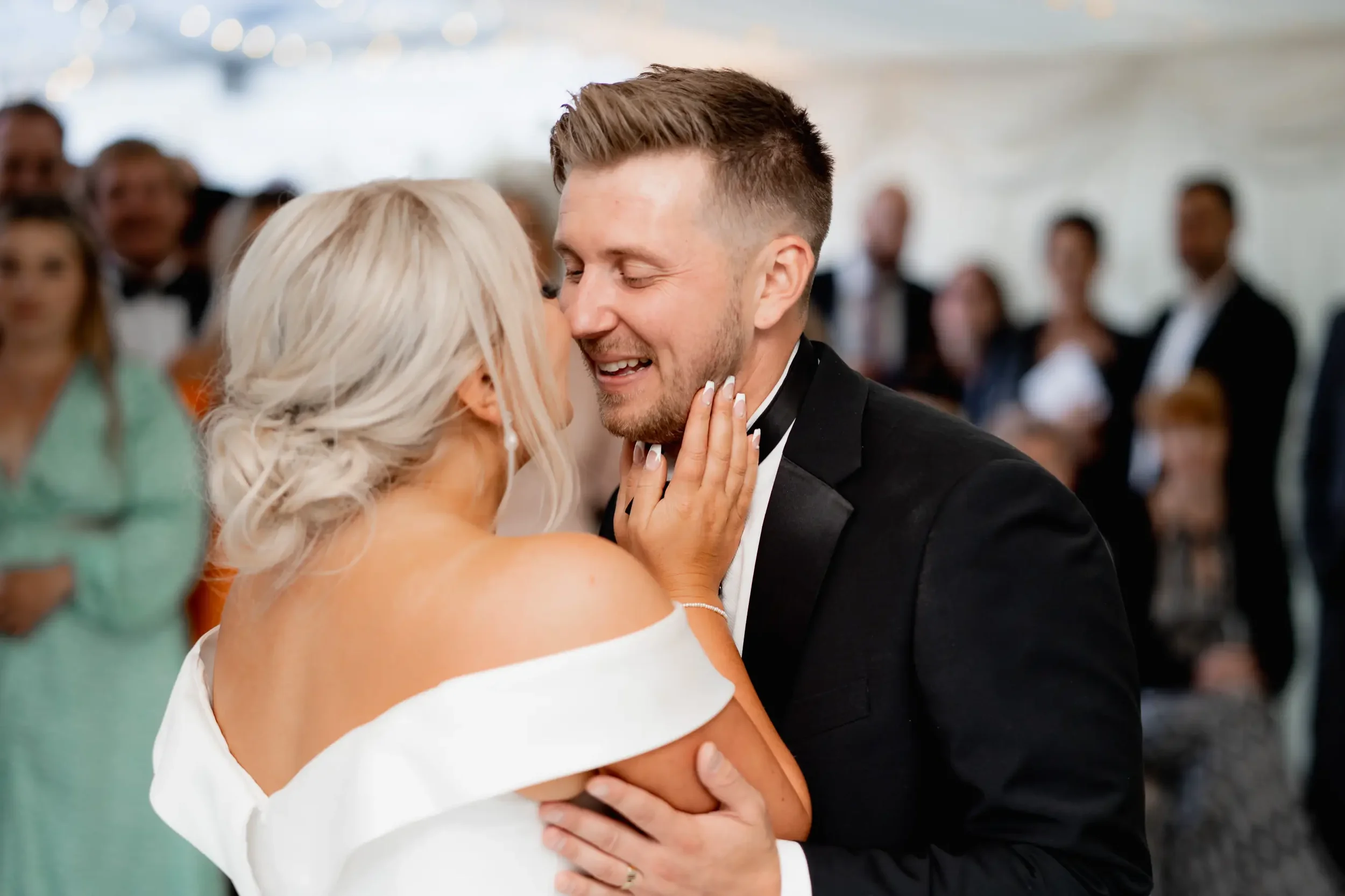 Bride and groom sharing a first dance at their wedding reception, surrounded by guests.