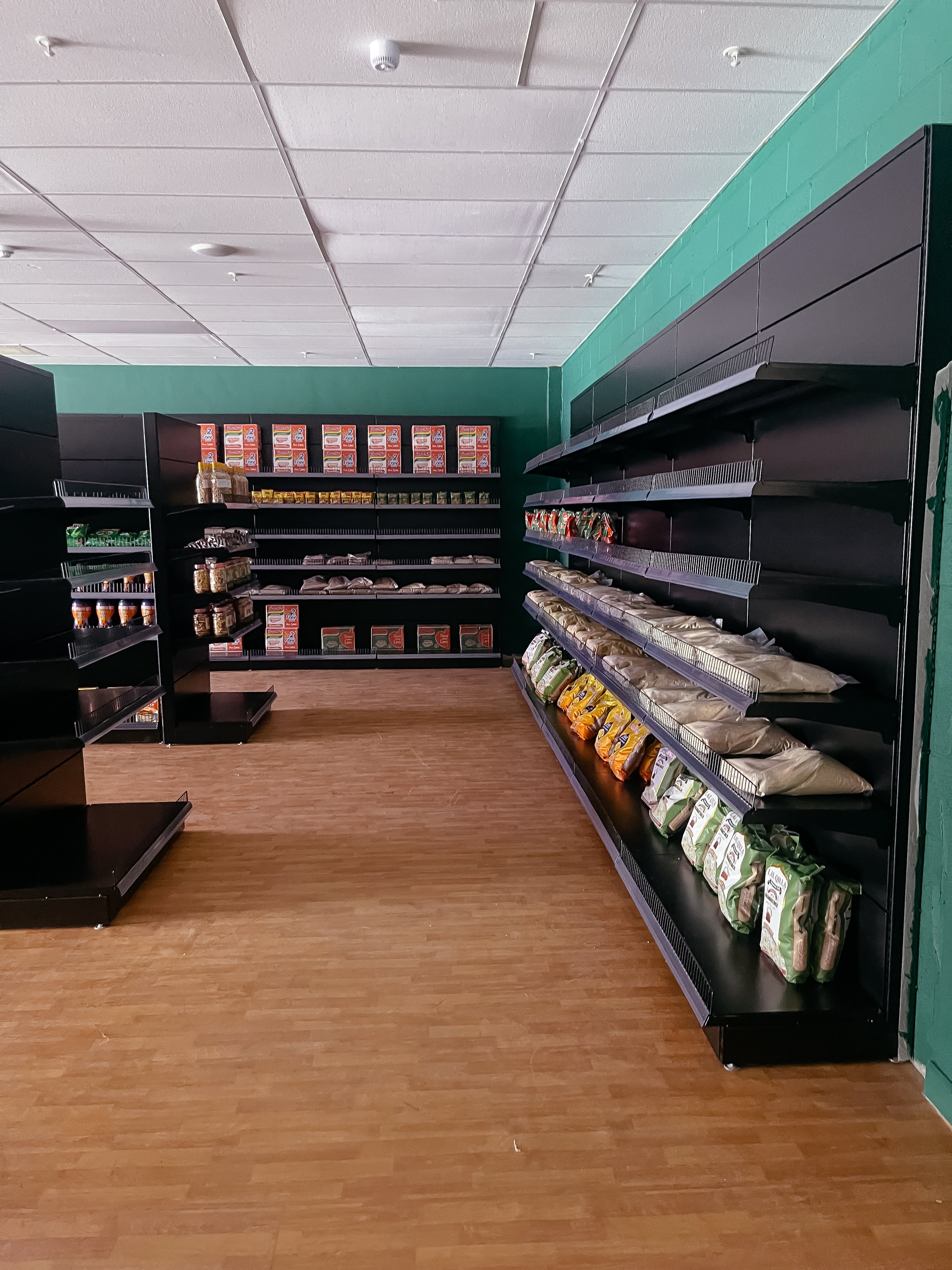 Empty store shelves in a grocery store, with mostly snacks and packaged food items.