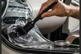 Person using a brush to clean a washing machine drum.