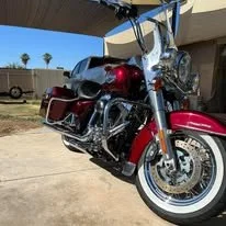 Red touring motorcycle with chrome accents parked on a driveway under a shaded cover.