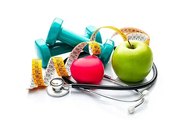 Green apple and red apple, blue dumbbells, measuring tape, and stethoscope on a white background, symbolizing health and fitness.