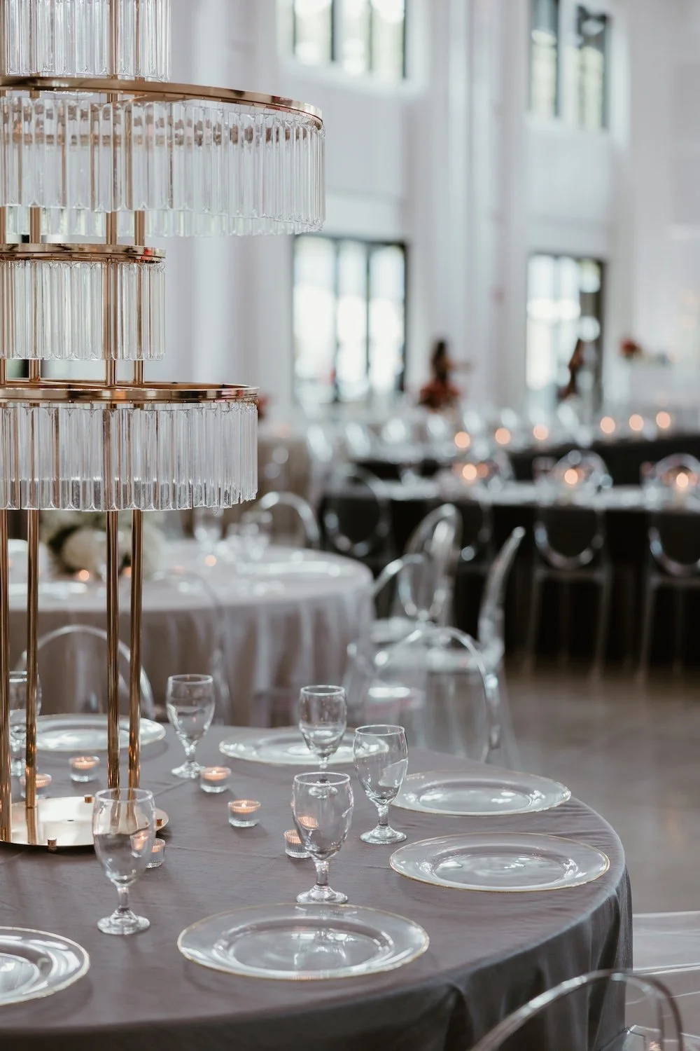 Sophisticated reception tables with white floral centerpieces, gray linens, and crystal glassware