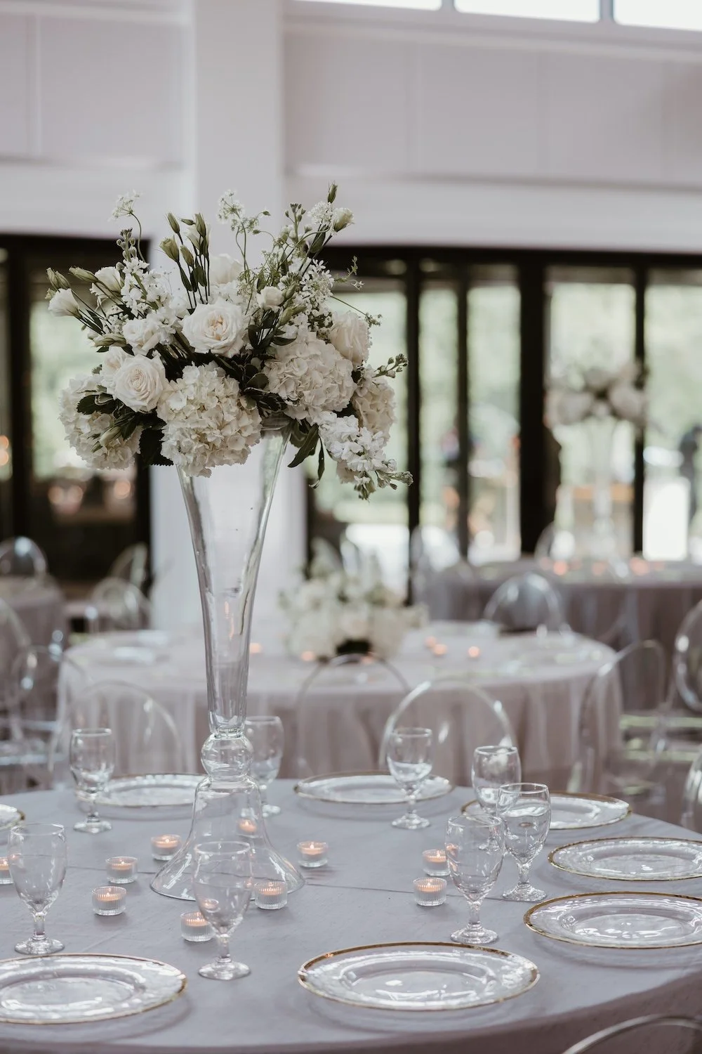 Sophisticated reception tables with white floral centerpieces, gray linens, and crystal glassware