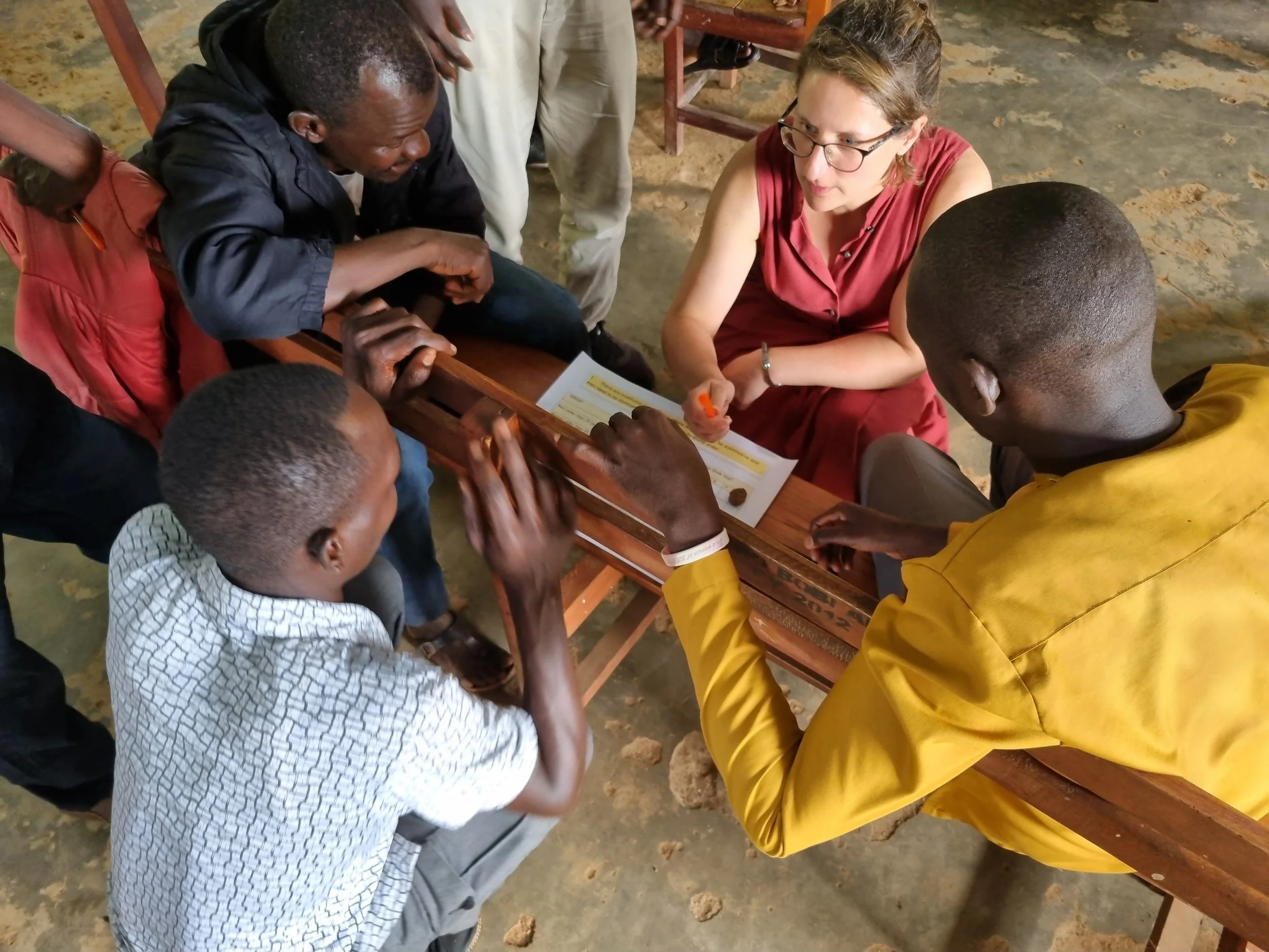 Photo taken from above looking down on a group of black men in a workshop in conversation with a white woman facilitator