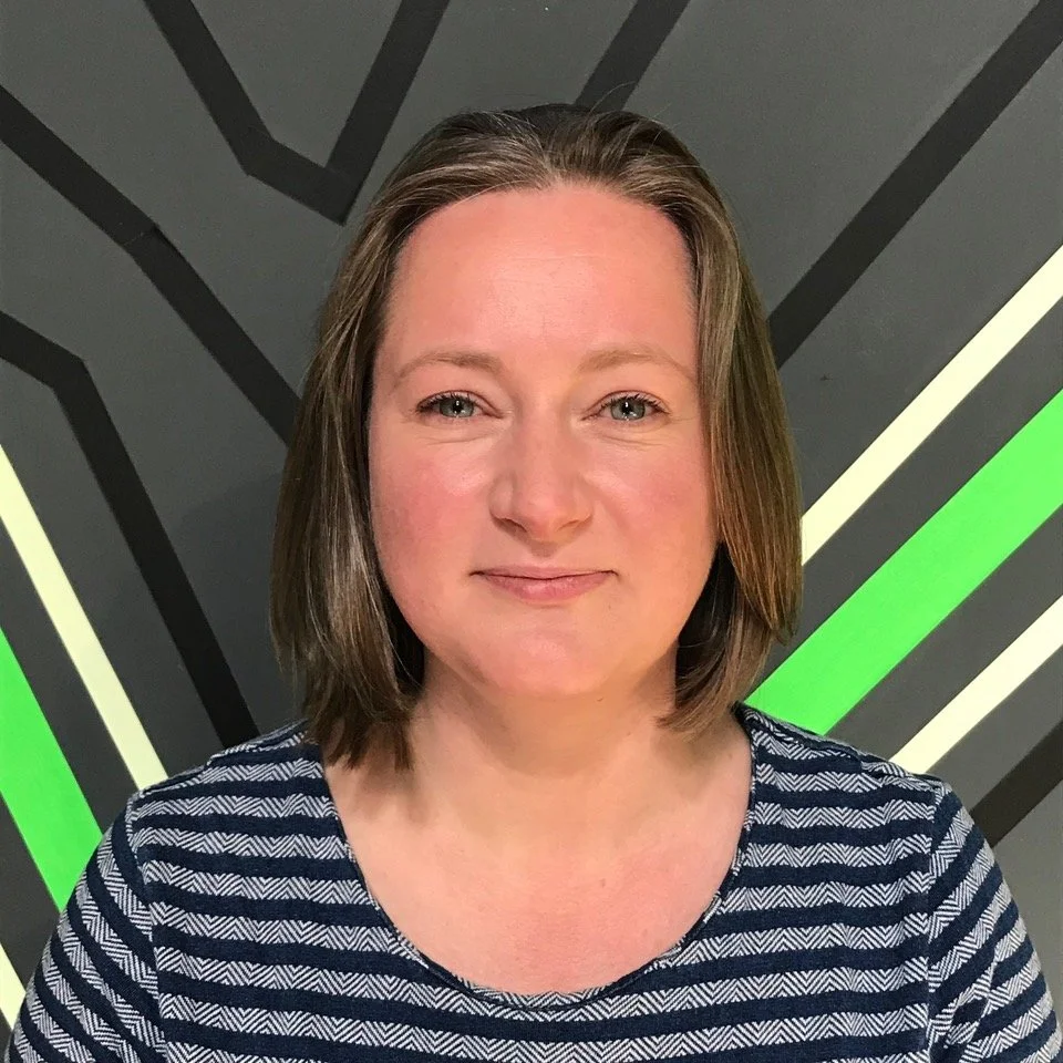 Photo of a white woman wearing a striped top smiling and looking directly at the camera