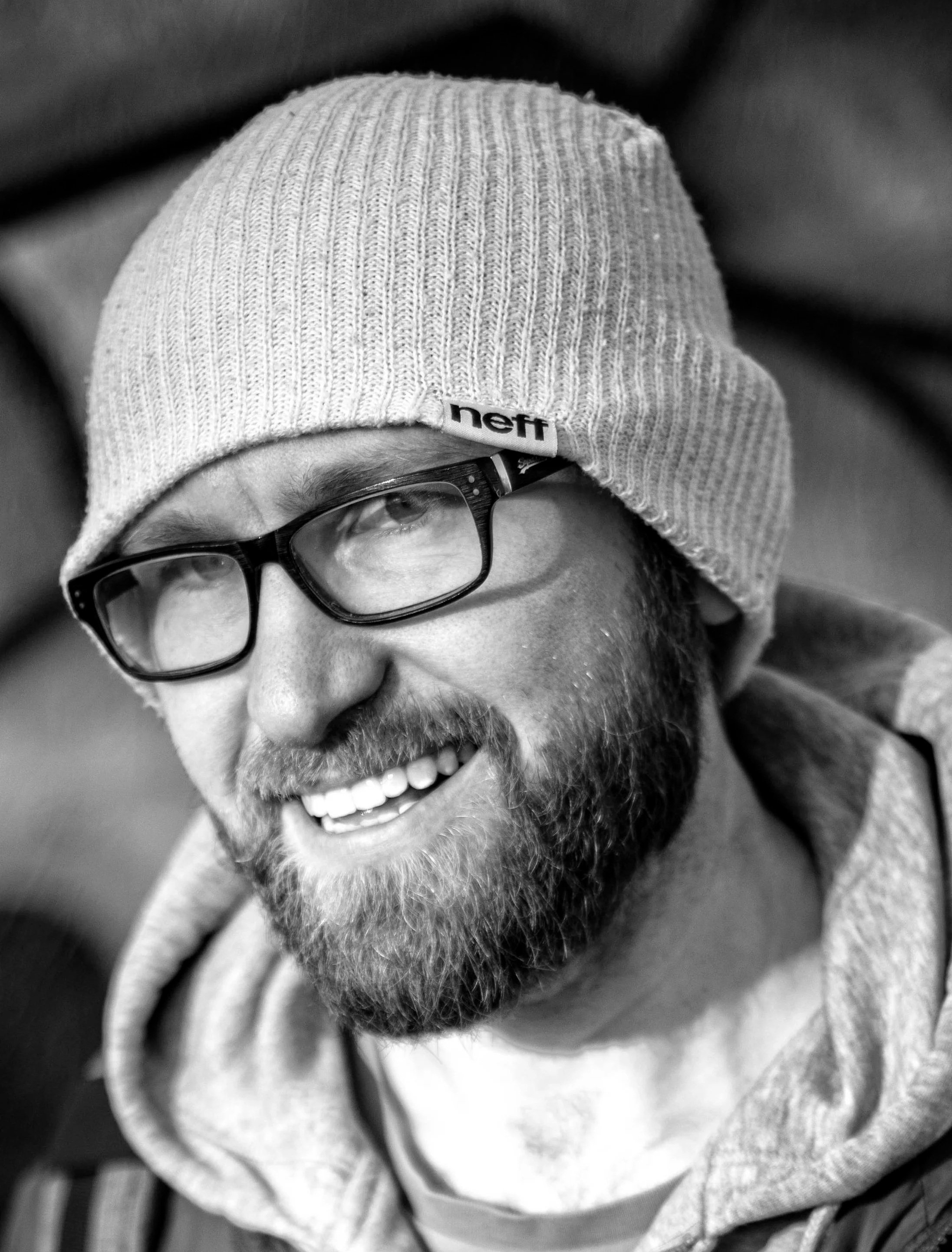 Black and white profile photo of a white man with glasses and a beard wearing a beanie hat