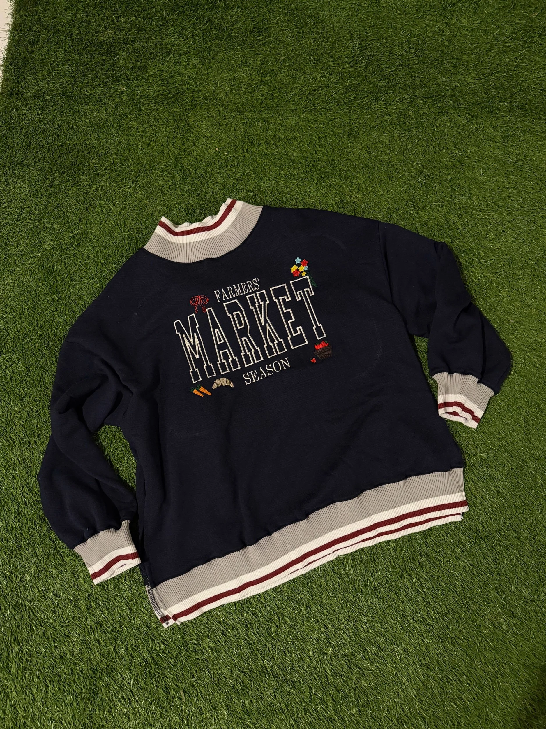 Navy blue mock neck with farmers' market season across the chest and little designs around it. 