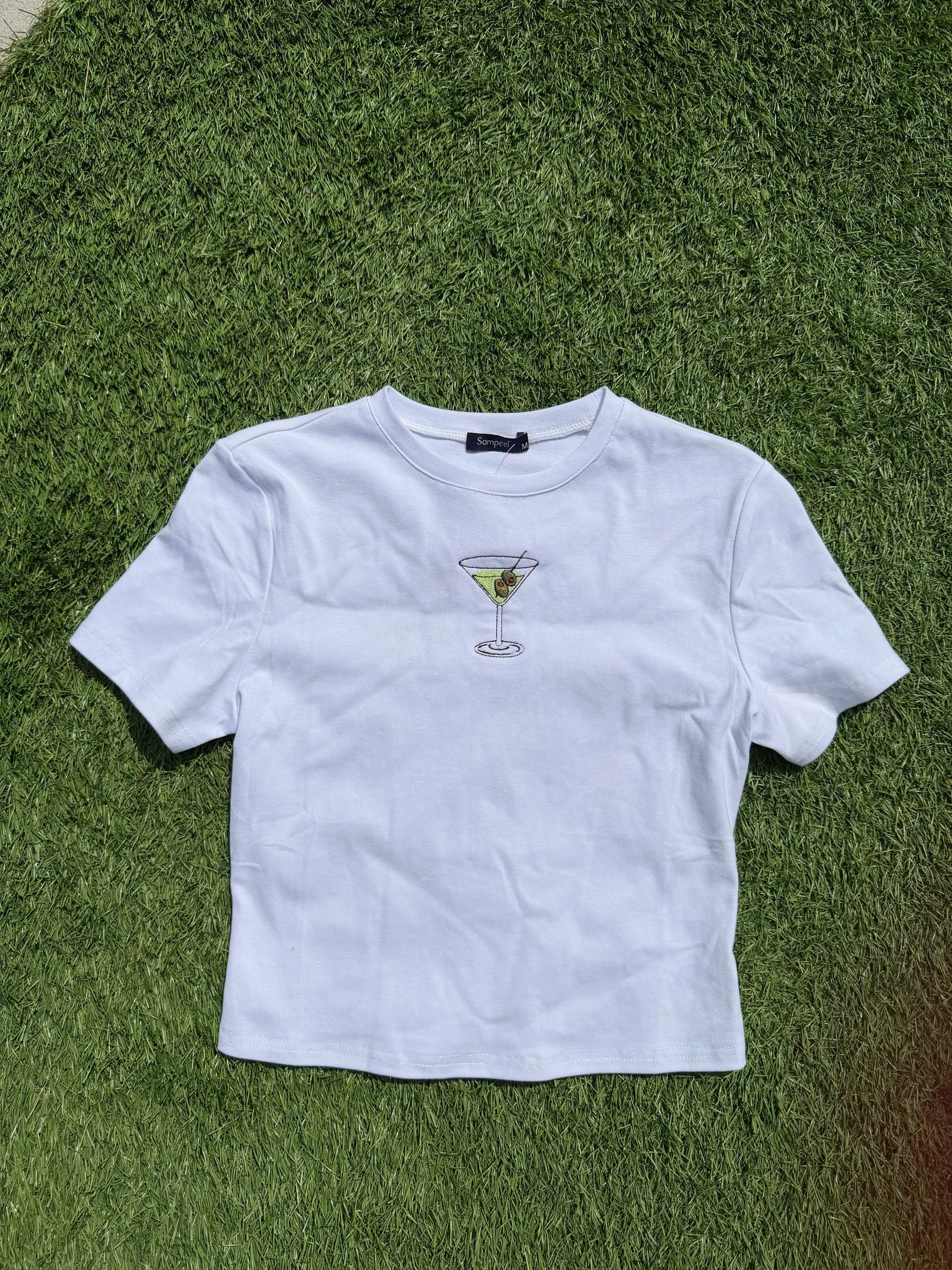 White baby tee with a martini and olives on it.