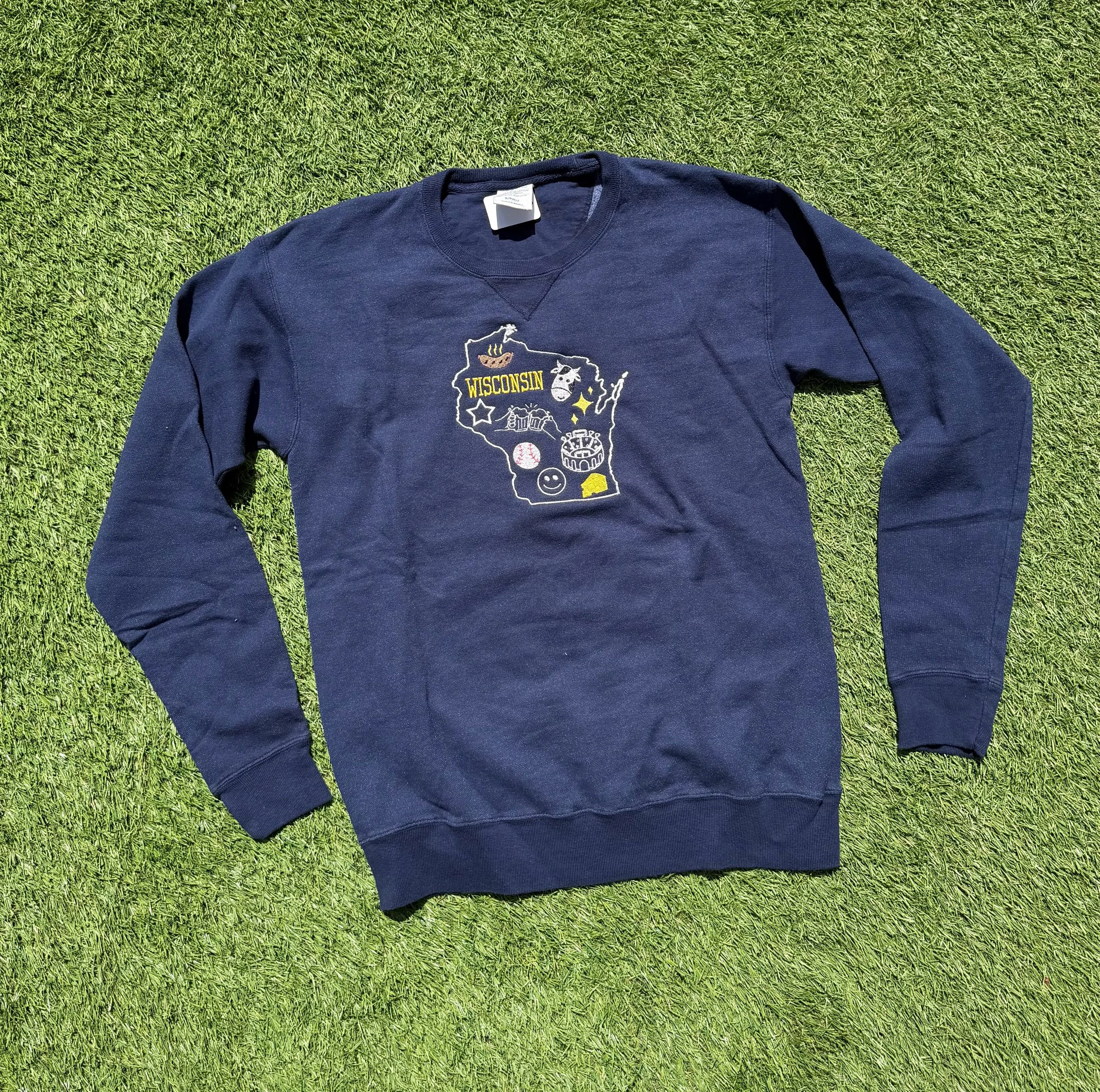 Navy blue crewneck with wisconsin and small icons on it. 