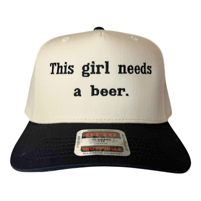 A trucker-style hat with a cream front panel and black brim, featuring the text "This girl needs a beer."