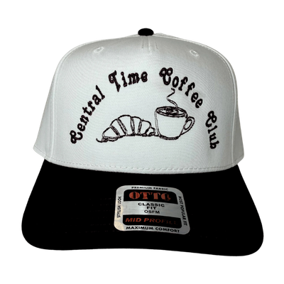 A white and black trucker hat with the logo 'Central Time Coffee Club' and images of a croissant and a coffee cup embroidered on the front.