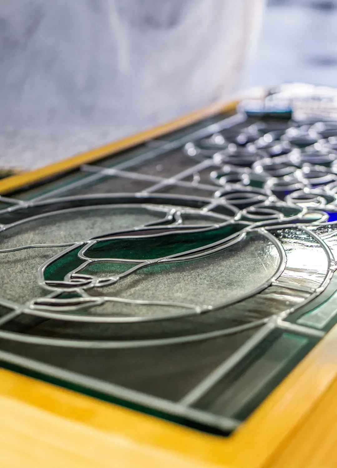 Detailaufnahme einer kunstvollen Bleiverglasung mit filigranen Bleiruten und farbigen Glaselementen, die in der Werkstatt der Glaserei Cremer & Bürgerhausen restauriert oder gefertigt wird.