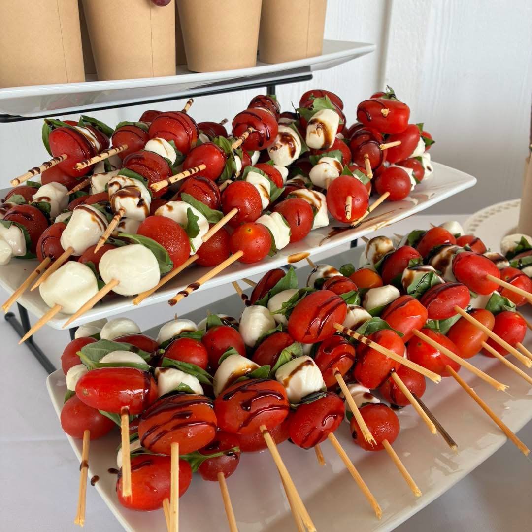 Platter of tomato, mozzarella, basil, and balsamic glaze skewers on a serving tray.