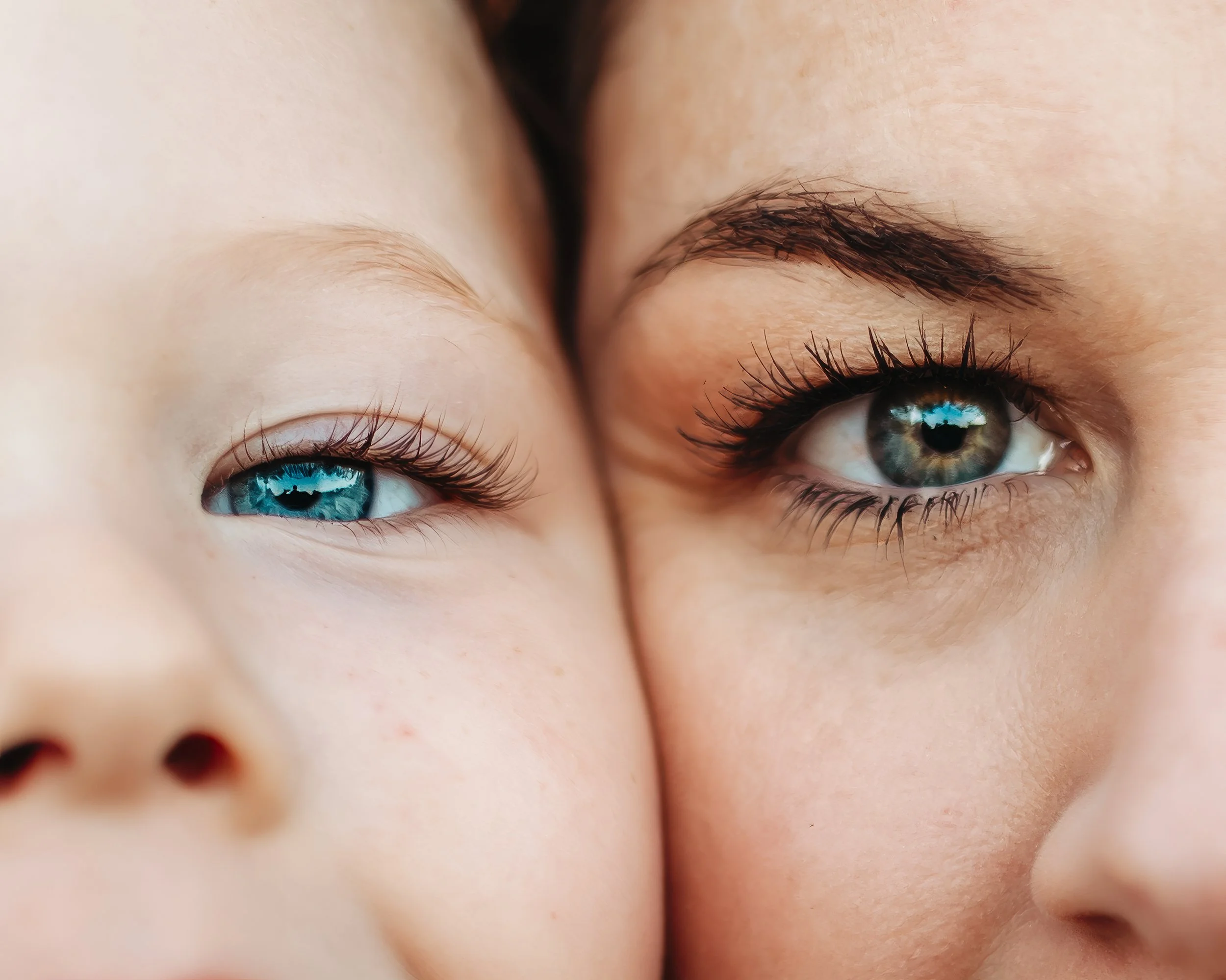 Close-up of two faces, a woman and a child, showing their blue eyes and eyebrows.