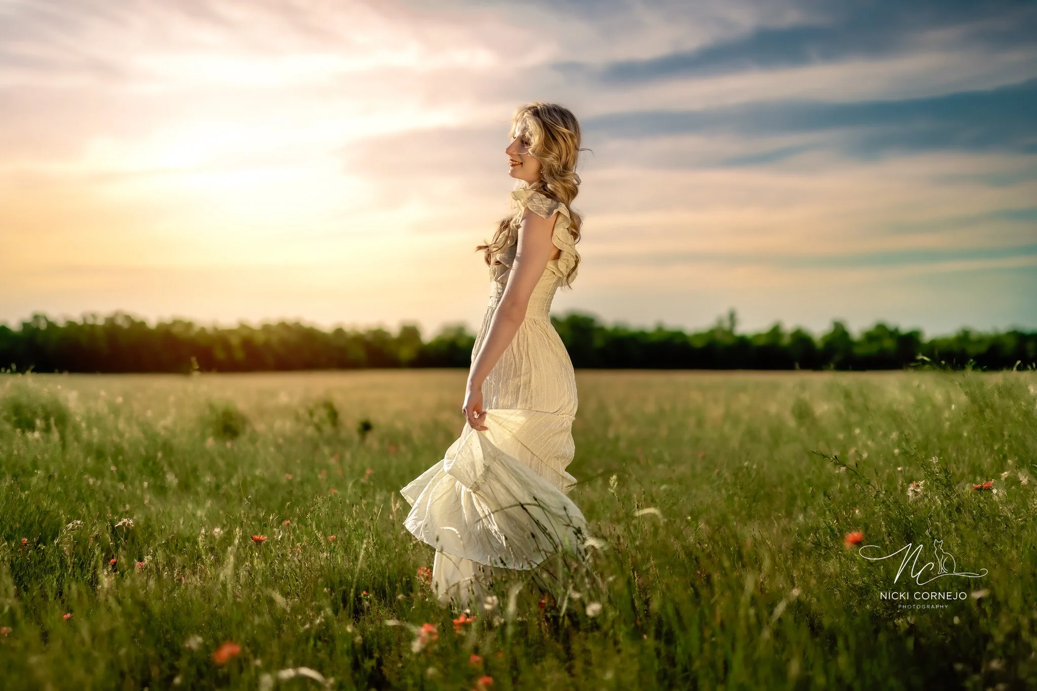 Senior portrait session of a girl with a flowy dress in a field during golden hour