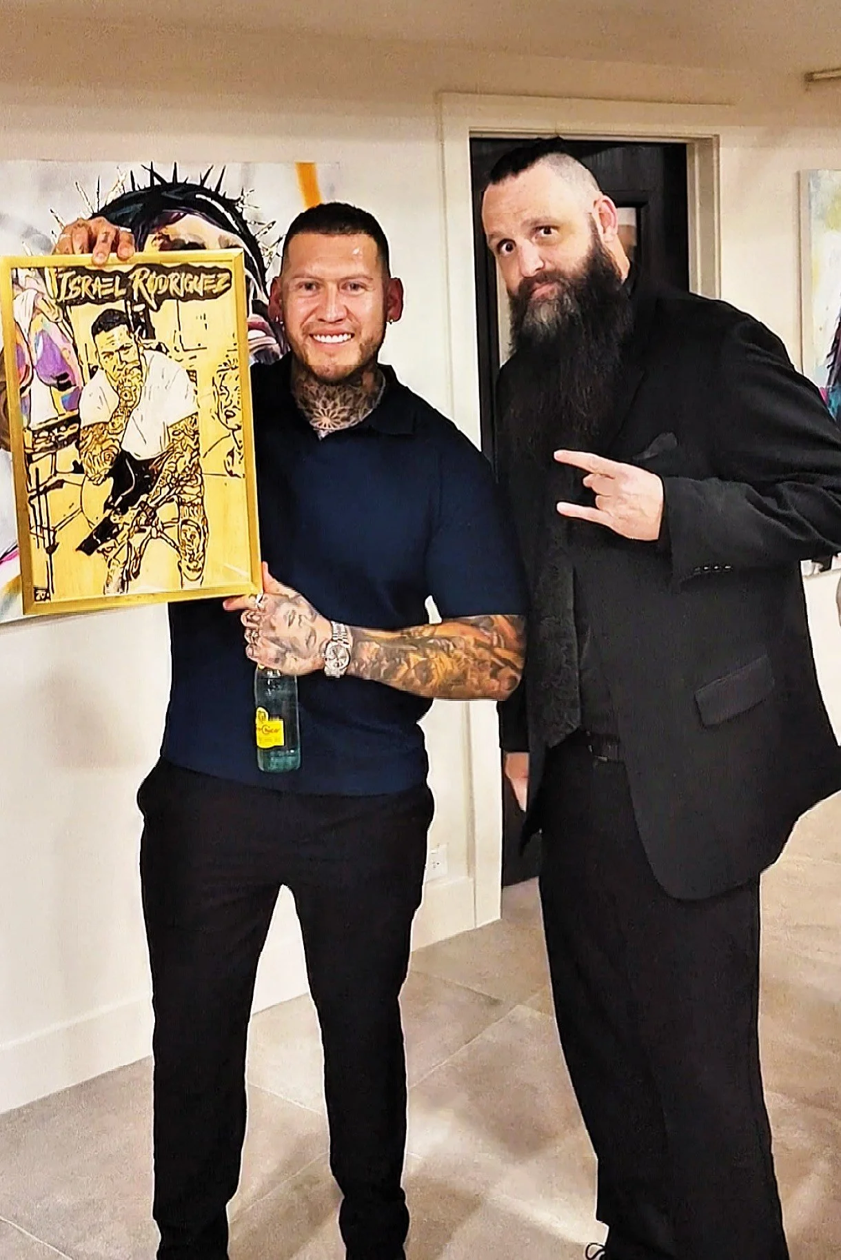 Mohawk Wyatt posing with Israel Rodriguez at his art show in Denver, Colorado with woodburning portrait he created for famous  famous artist
