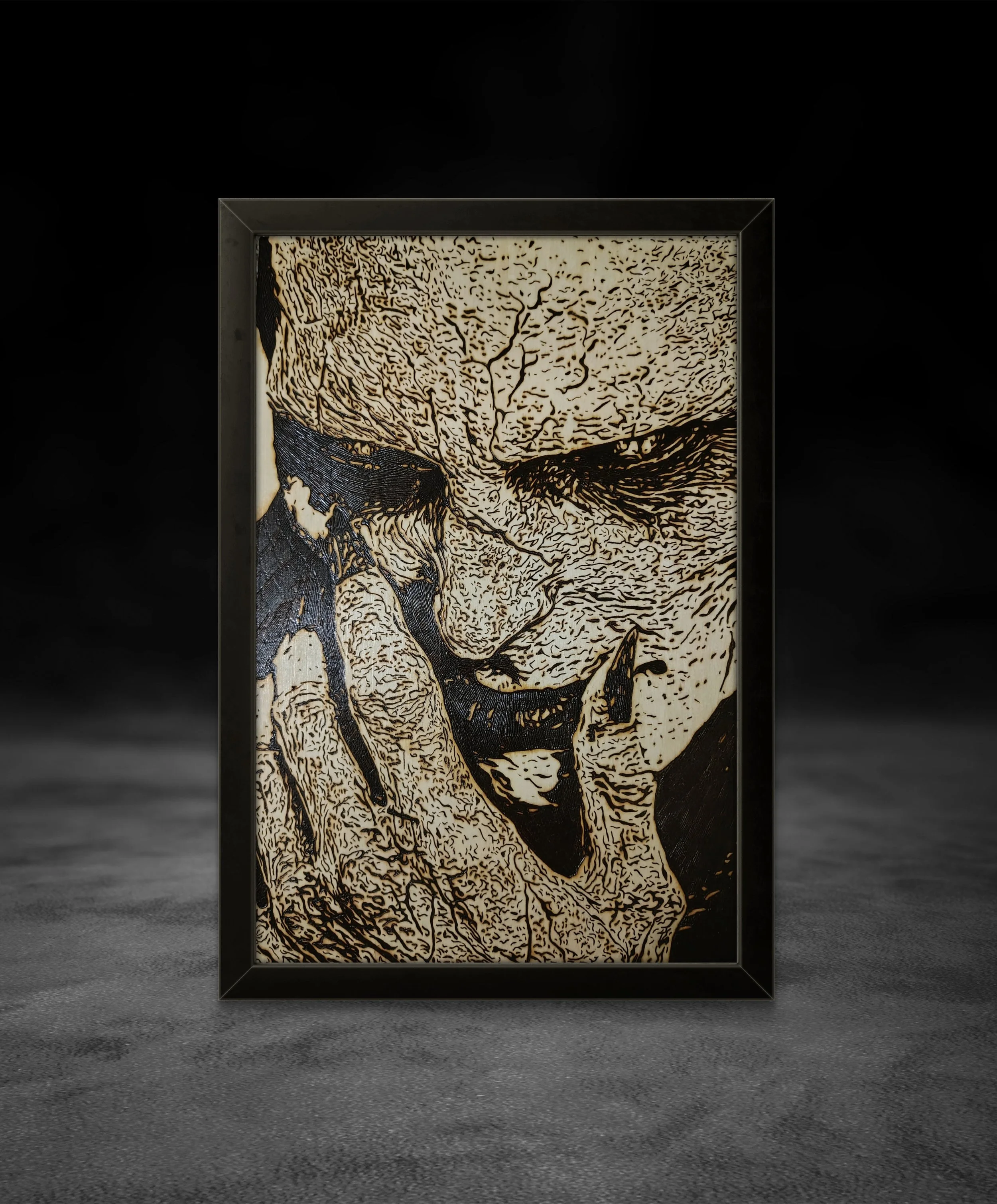 Dark expressive wood-burned wall art with heavy linework and organic grain texture, framed in black against a studio backdrop
