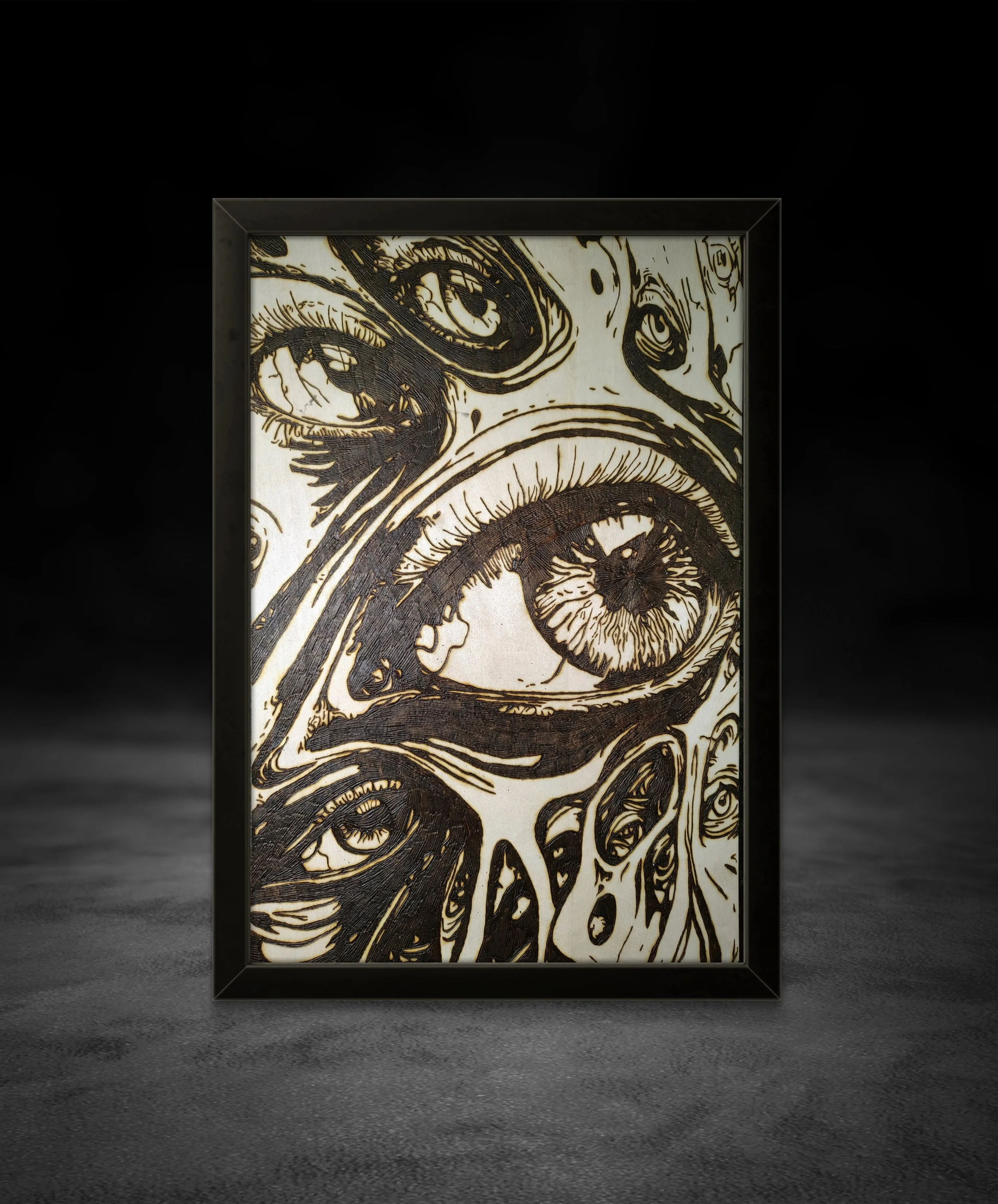 Close-up view of detailed wood-burned eye artwork emphasizing texture, depth, and organic burn patterns on basswood