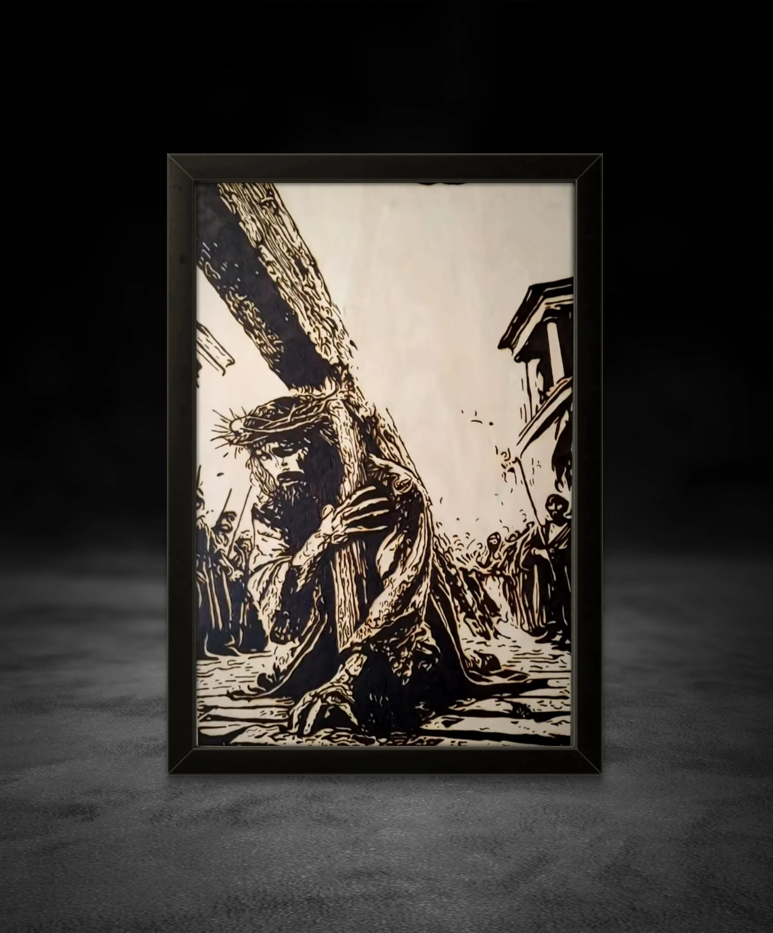 Hand-burned basswood artwork depicting a figure collapsing beneath a cross, framed wall display