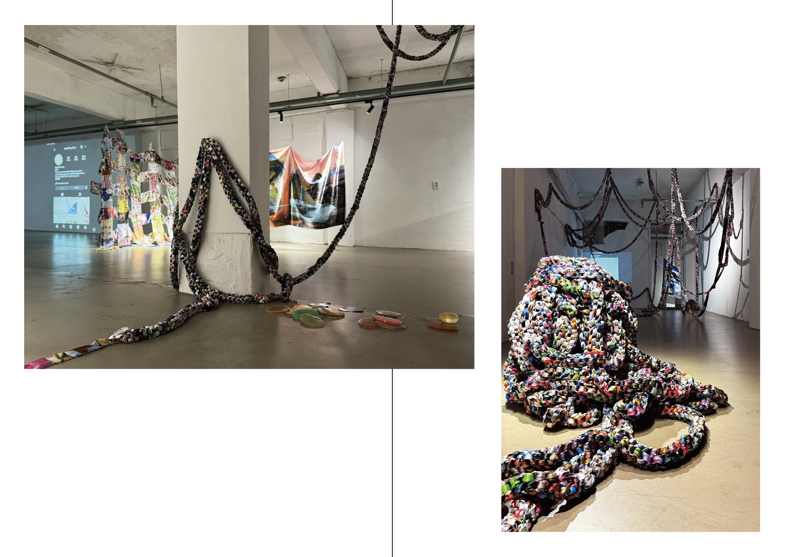 An art installation featuring colorful, braided rope-like structures hanging from the ceiling and winding across the floor, with a quilt-like fabric backdrop and scattered glass objects.