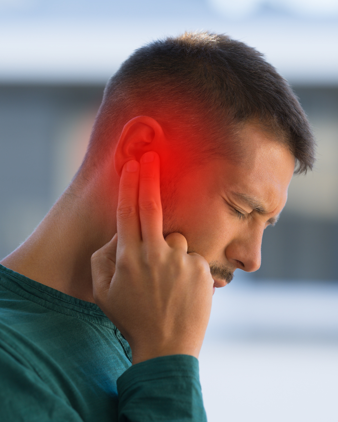 Man experiencing ear pain or discomfort, holding his ear with his hand, highlighted in red to indicate pain.