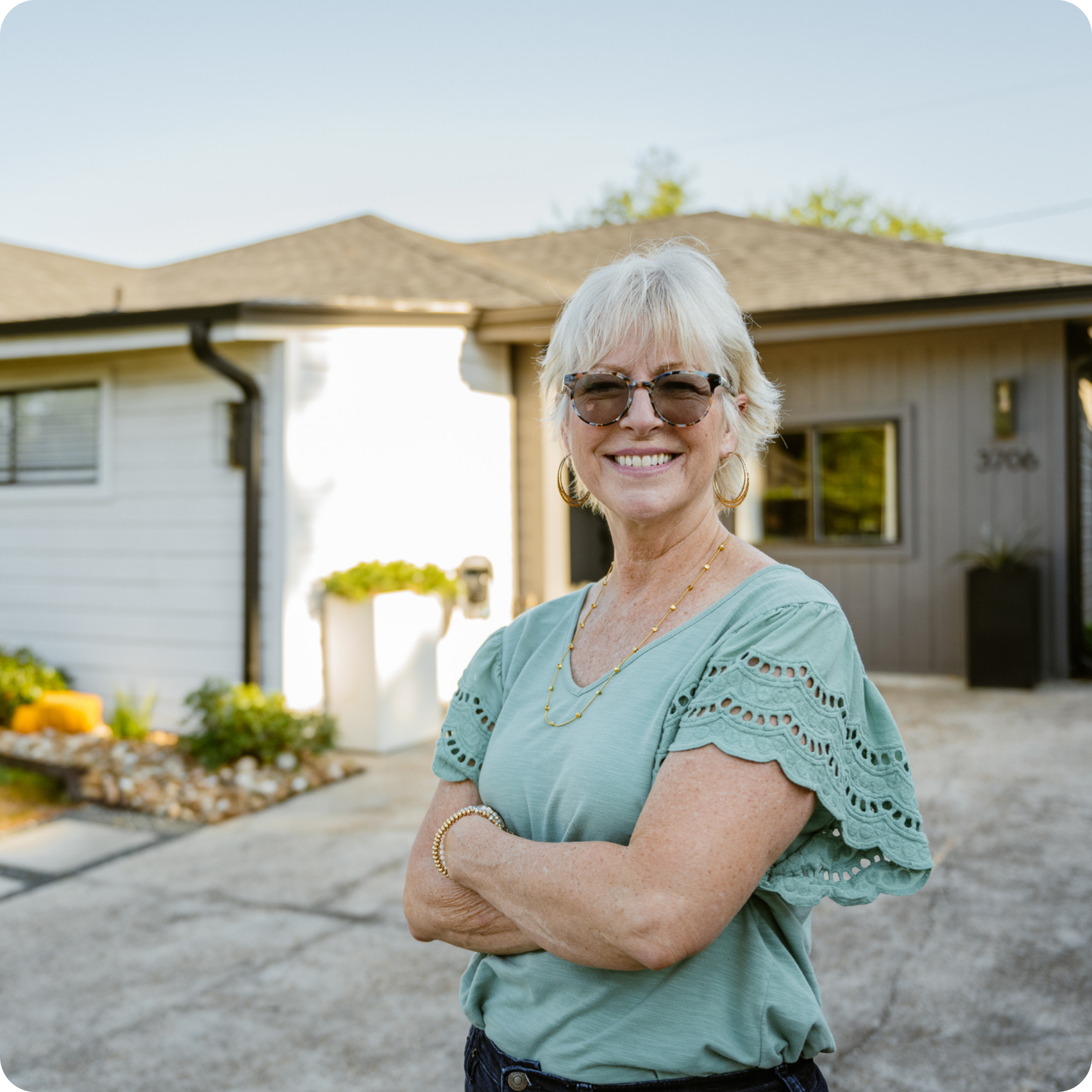 A woman standing excited in front of a home she just bought because of affordable housing advocacy.