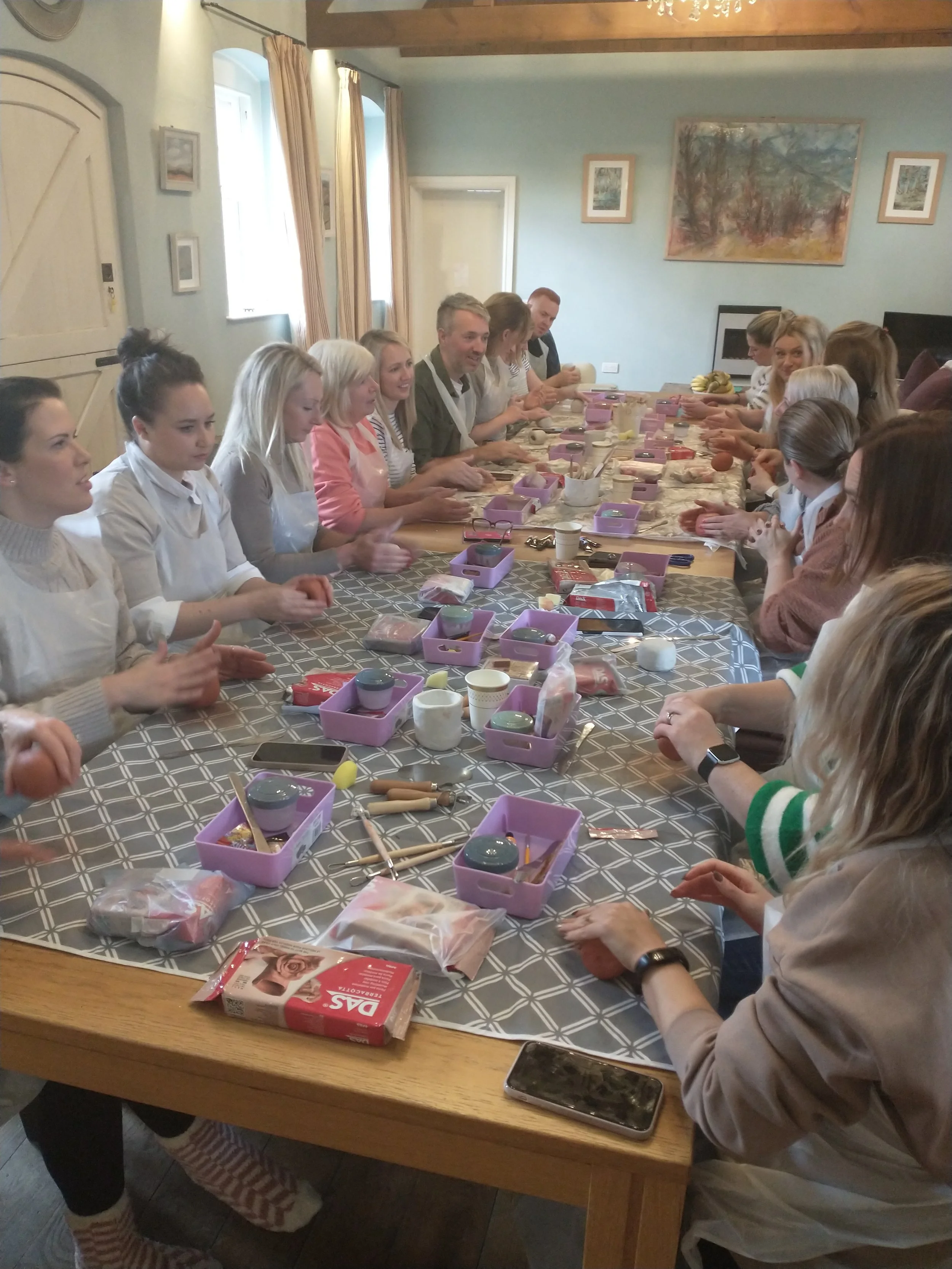 large group of friends making clay boob pots whilst seated at a table