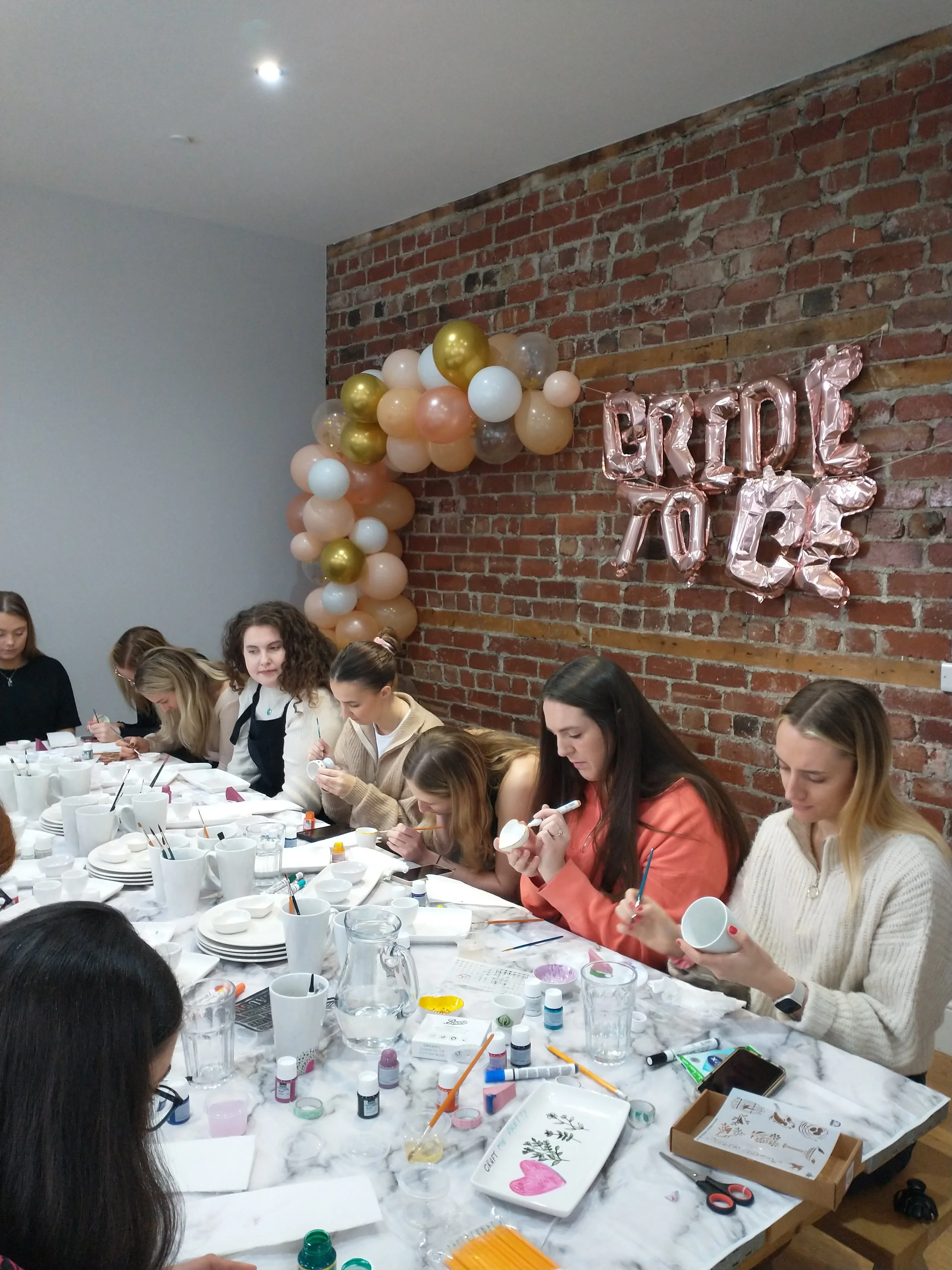 group of women painting ceramic pieces at the hen party
