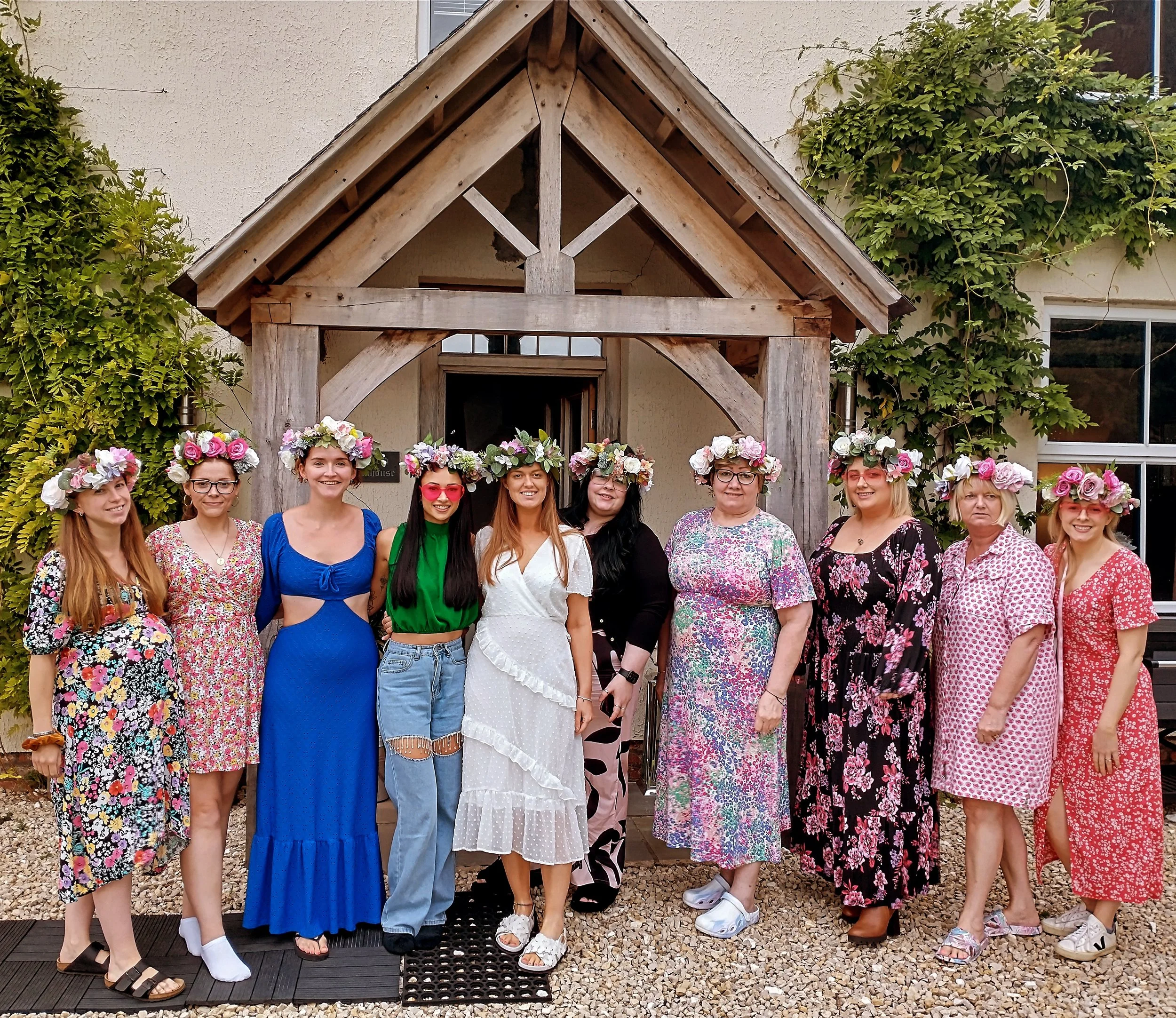 A group of smiling women wearing handmade faux flower crowns at a fun and creative hen party workshop in Bakewell