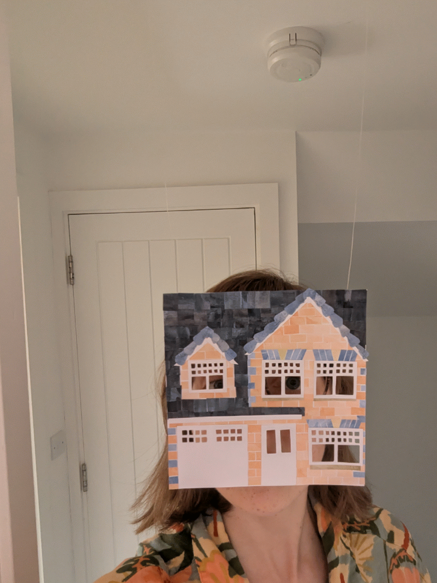 Jade peeking through a collaged paper house (her childhood home) in front of their face, with a door, windows, and a tiled roof.