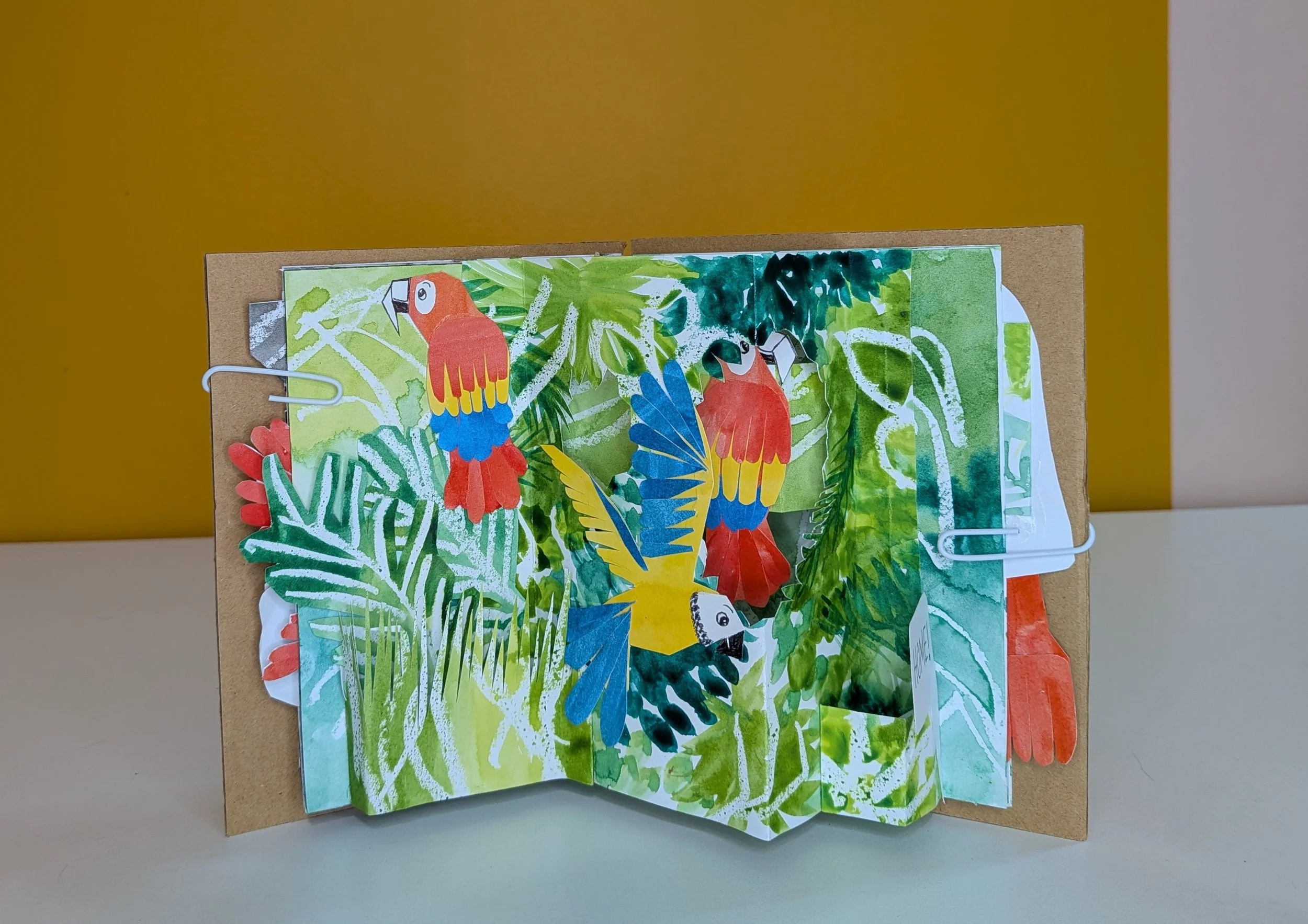 Collaged parrots in their home environment, all part of a pop-up scene.