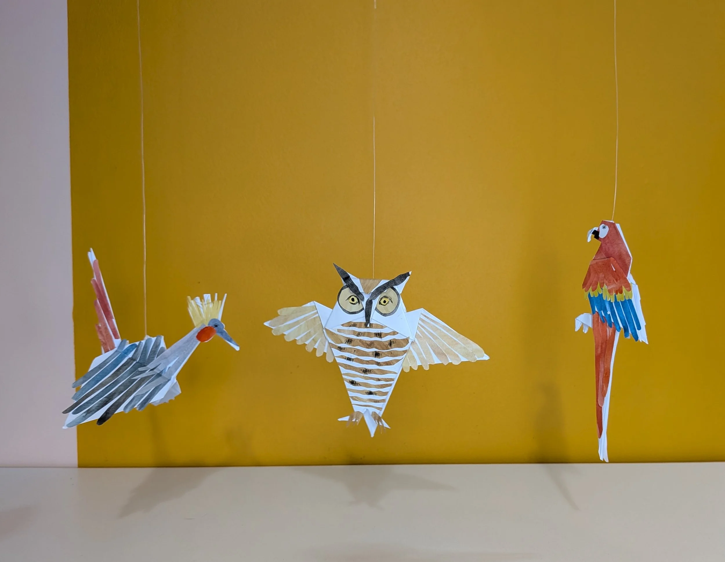 Three paper origami birds with painted collage details.
