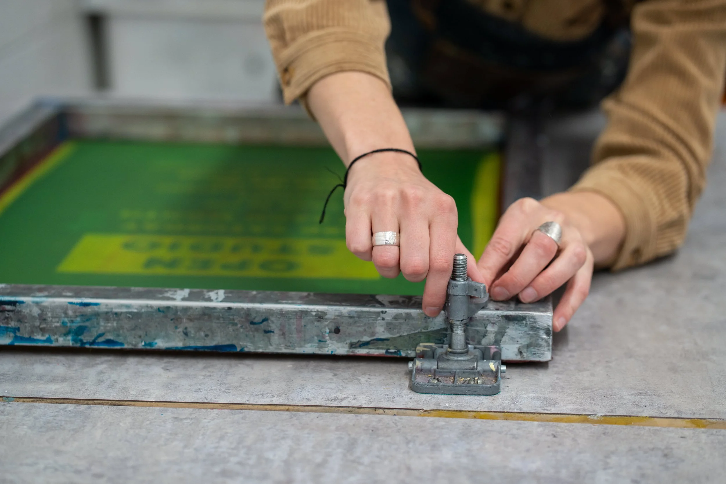 Person's hands adjusting printing press on a worktable.