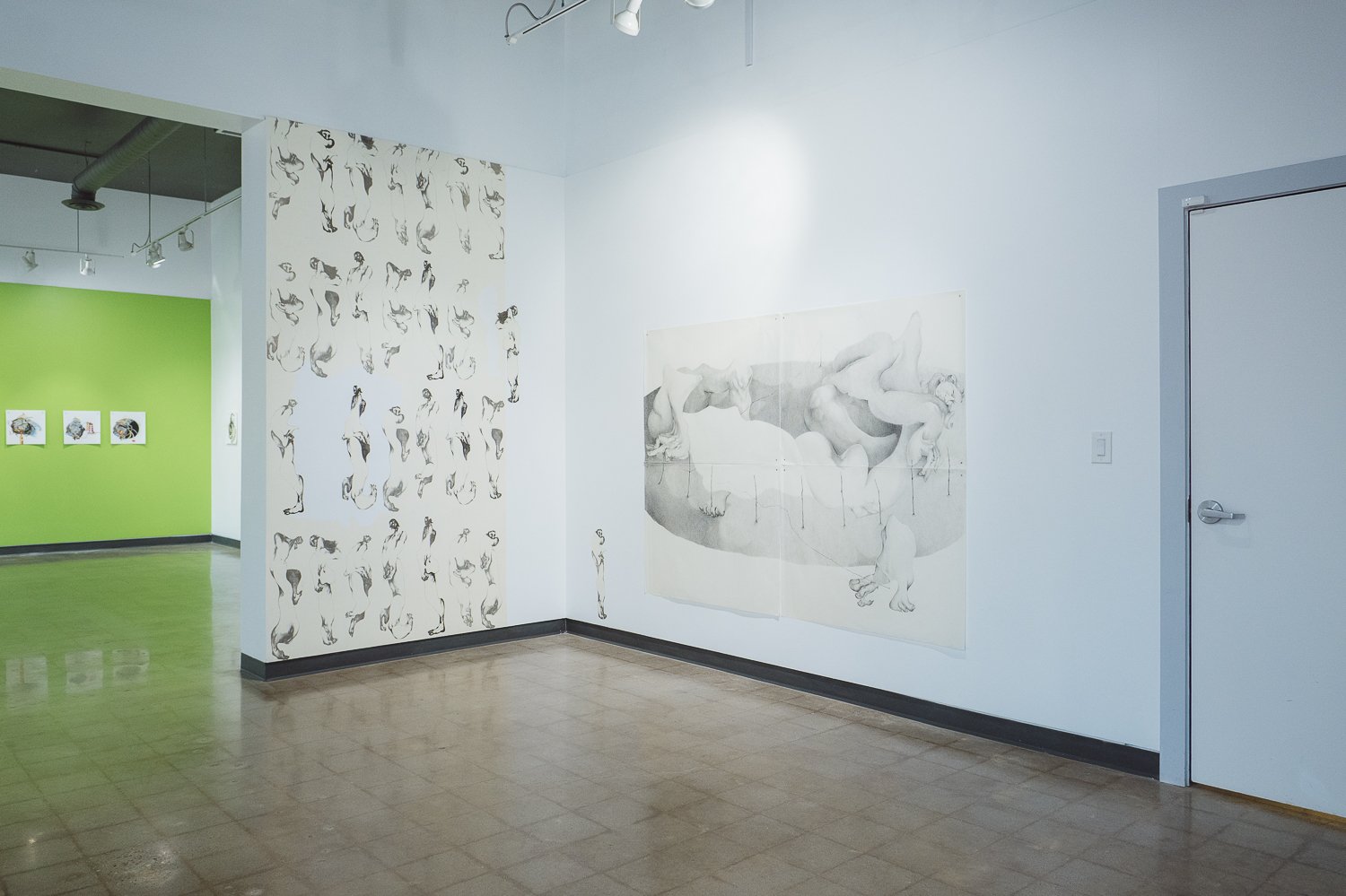 Art gallery with various black-and-white drawings of nude figures on the wall and a green-colored room in the background with framed artworks.