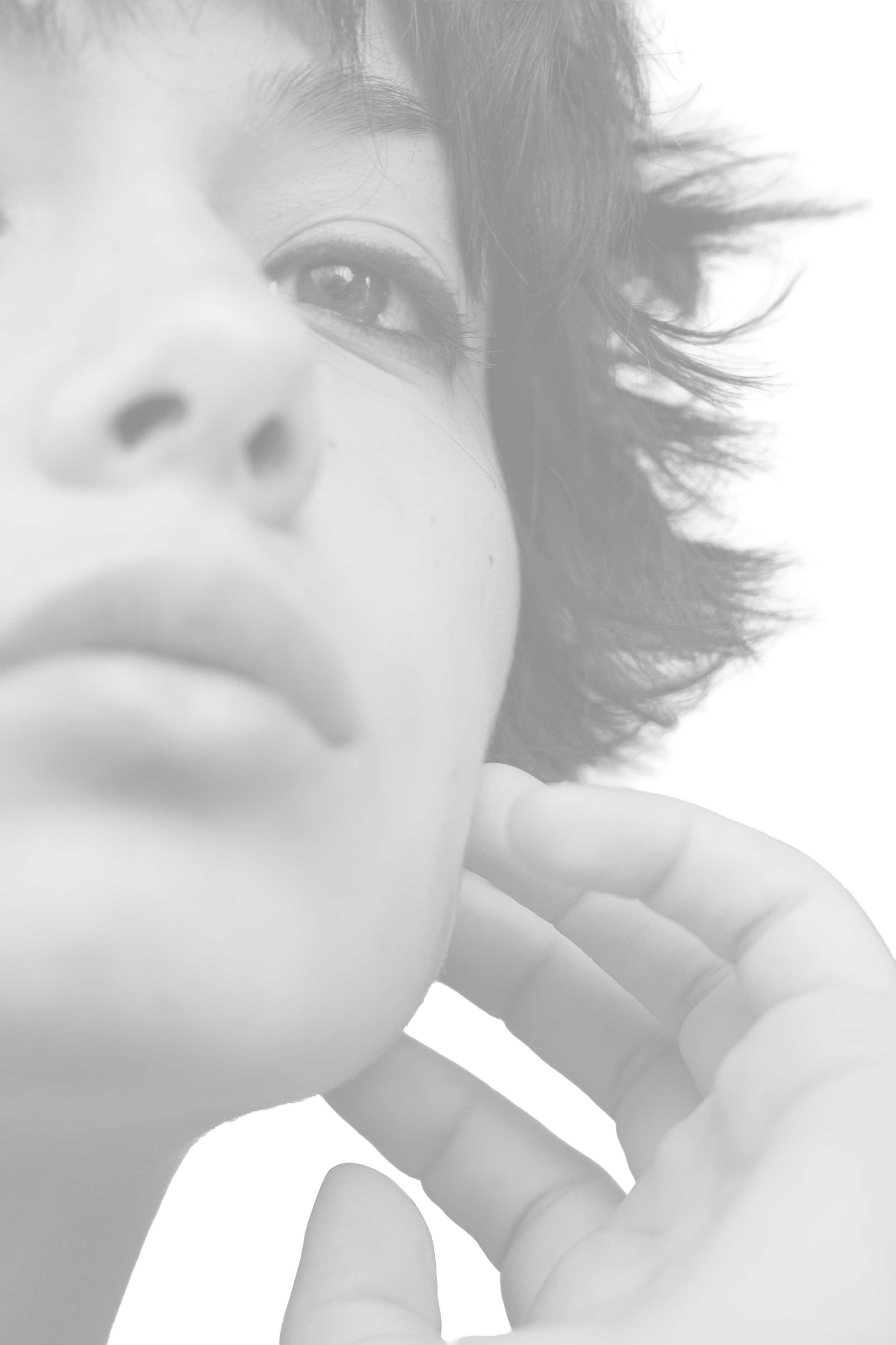 Ritratto in bianco e nero di una donna con capelli corti e occhi inquietanti, che tocca delicatamente il volto con la mano.