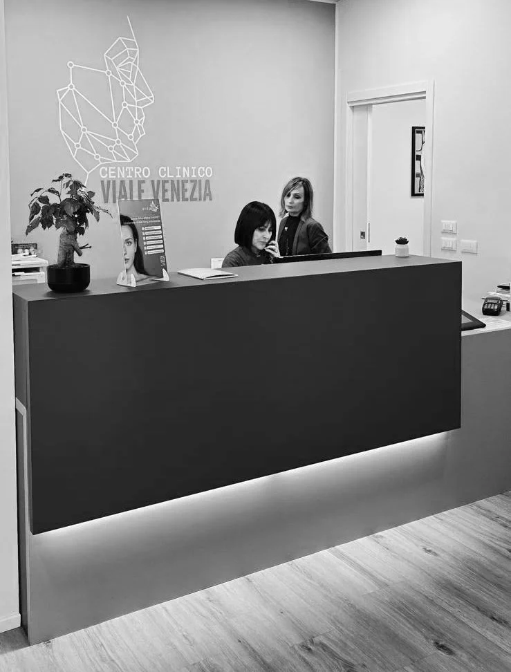 Reception presso il centro clinico Viale Venezia, con due donne dietro il bancone, decorazioni minimaliste e piante.
