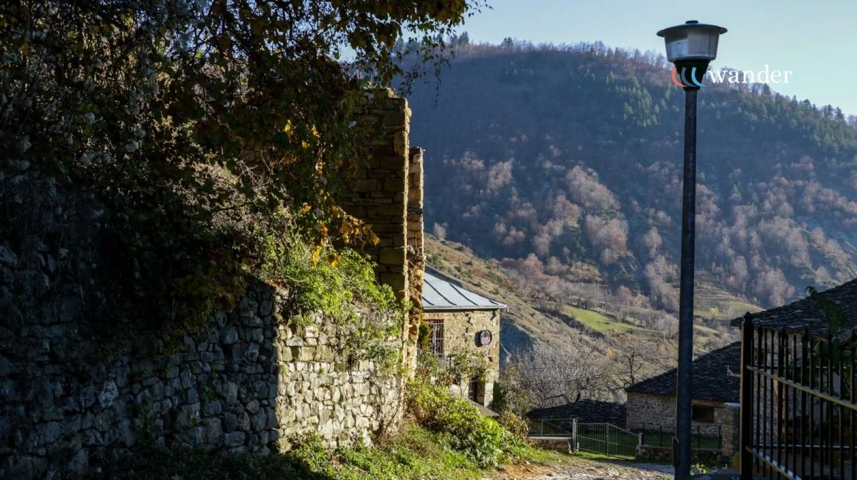 A rustic village scene with stone buildings, a street lamp, and a mountain in the background.