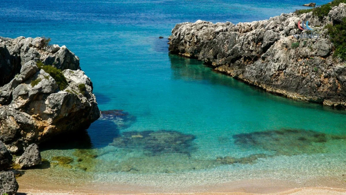 Clear blue water between rocky cliffs at a beach.