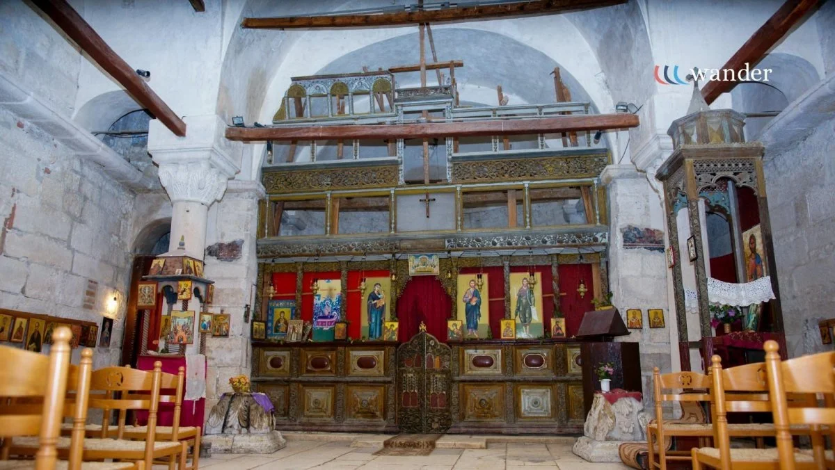 Interior of a church with an altar, religious icons, and wooden chairs.