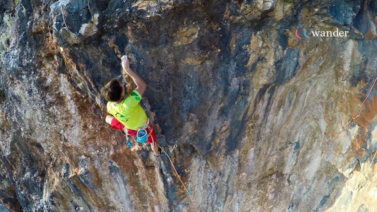 A person rock climbing on a steep cliff face with climbing gear and safety ropes.