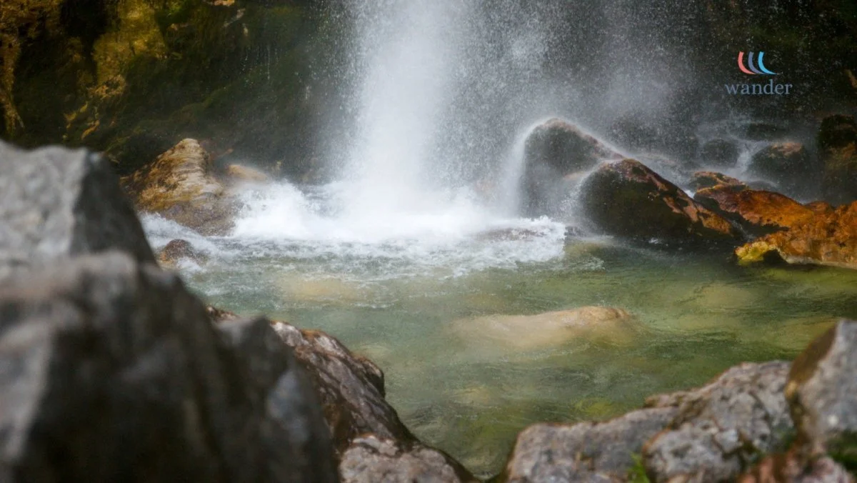 A small waterfall cascading into a rocky stream surrounded by nature.